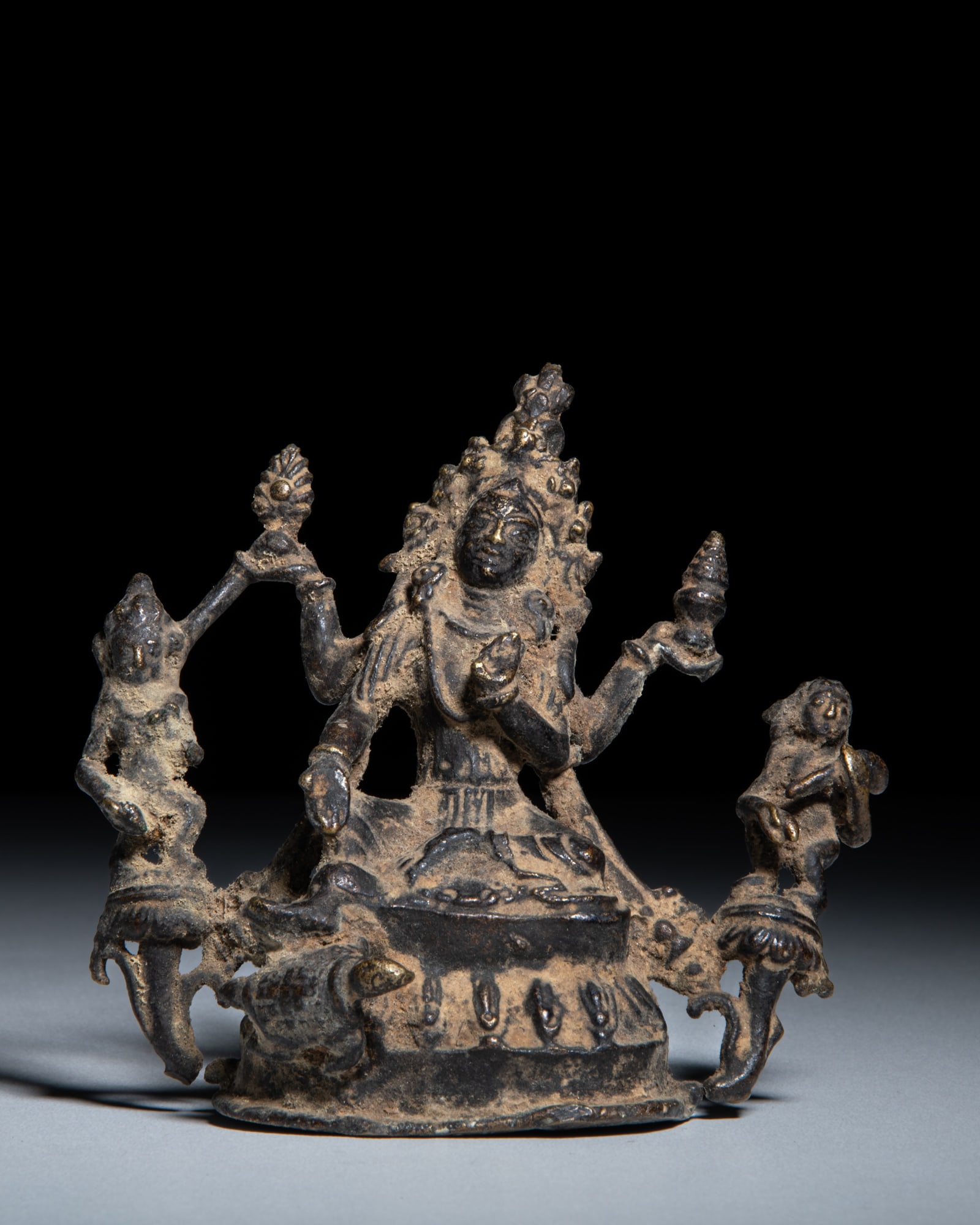 A COPPER ALLOY FIGURE OF A FOUR-ARMED FEMININE DEITY Nepal, 20th Century depicts a four-armed (1 of 3)