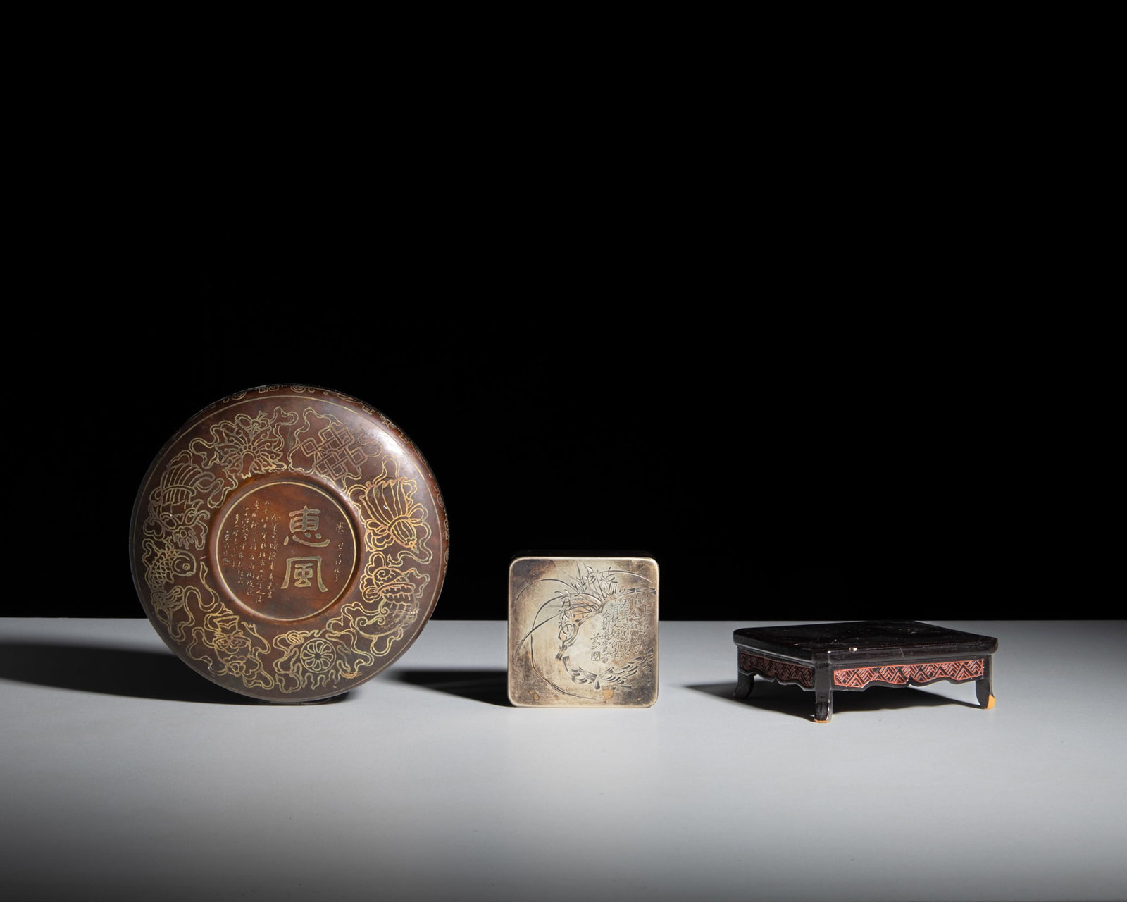 A COLLECTION OF TWO SCHOLAR'S WRITTING TOOLS China, 20th century including a carved brass: A COLLECTION OF TWO SCHOLAR'S WRITTING TOOLS China, 20th century including a carved brass square-shaped box, signed 'Beiping, Yichang', with a wooden stand; and a circular ink box with an inkstone ins