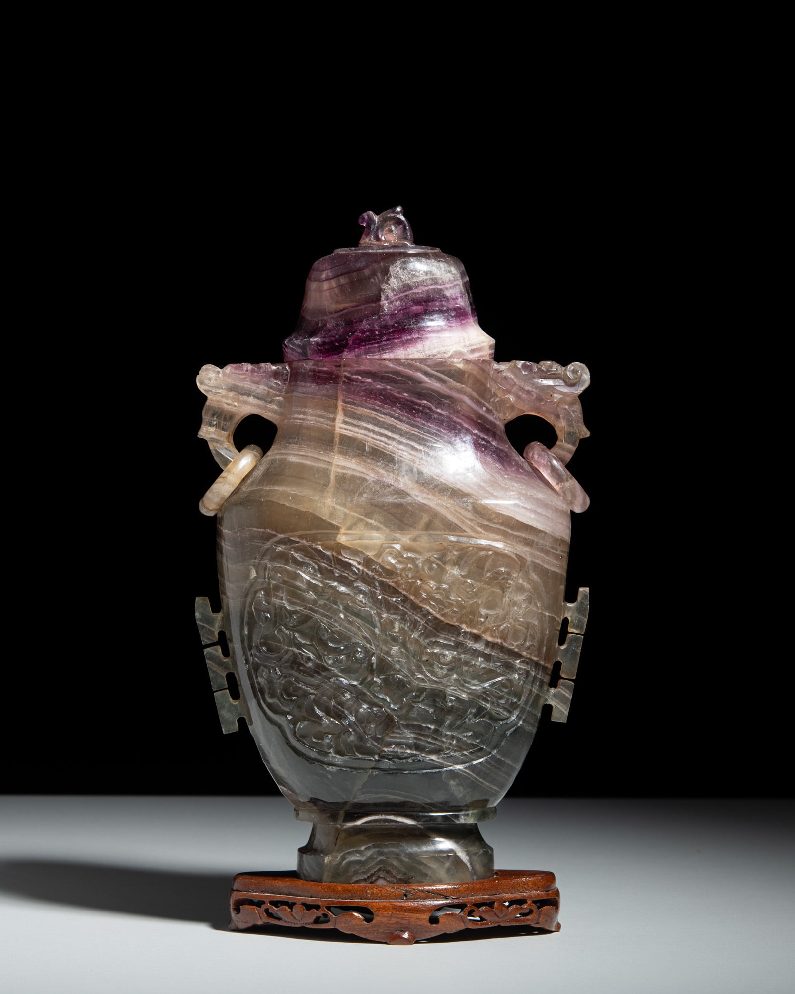 A CARVED DRAGON FLUORITE VASE WITH COVER AND WOODEN STAND 晚清 萤石辅: A CARVED DRAGON FLUORITE VASE WITH COVER AND WOODEN STAND 晚清 萤石辅首龙纹盖瓶带木座 China, late 19th century H. 30.2 cm 