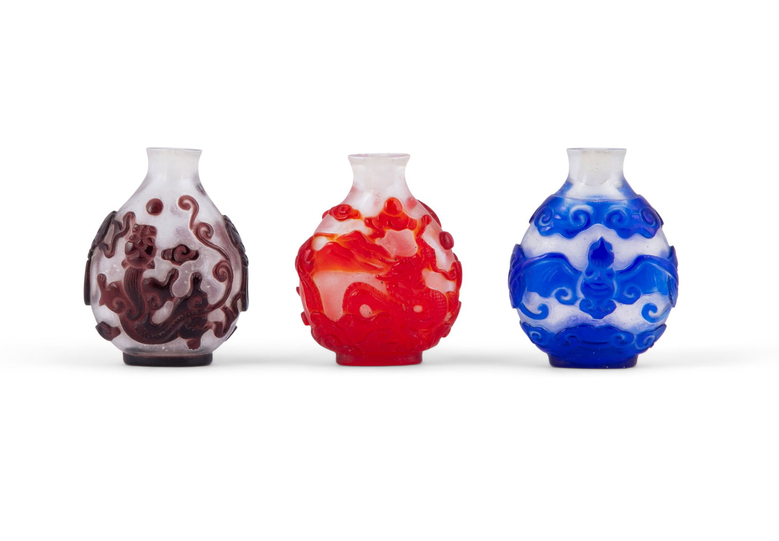 A GROUP OF THREE OVERLAY GLASS SNUFF BOTTLES In red, blue and dark purple colour, carved with (1 of 2)