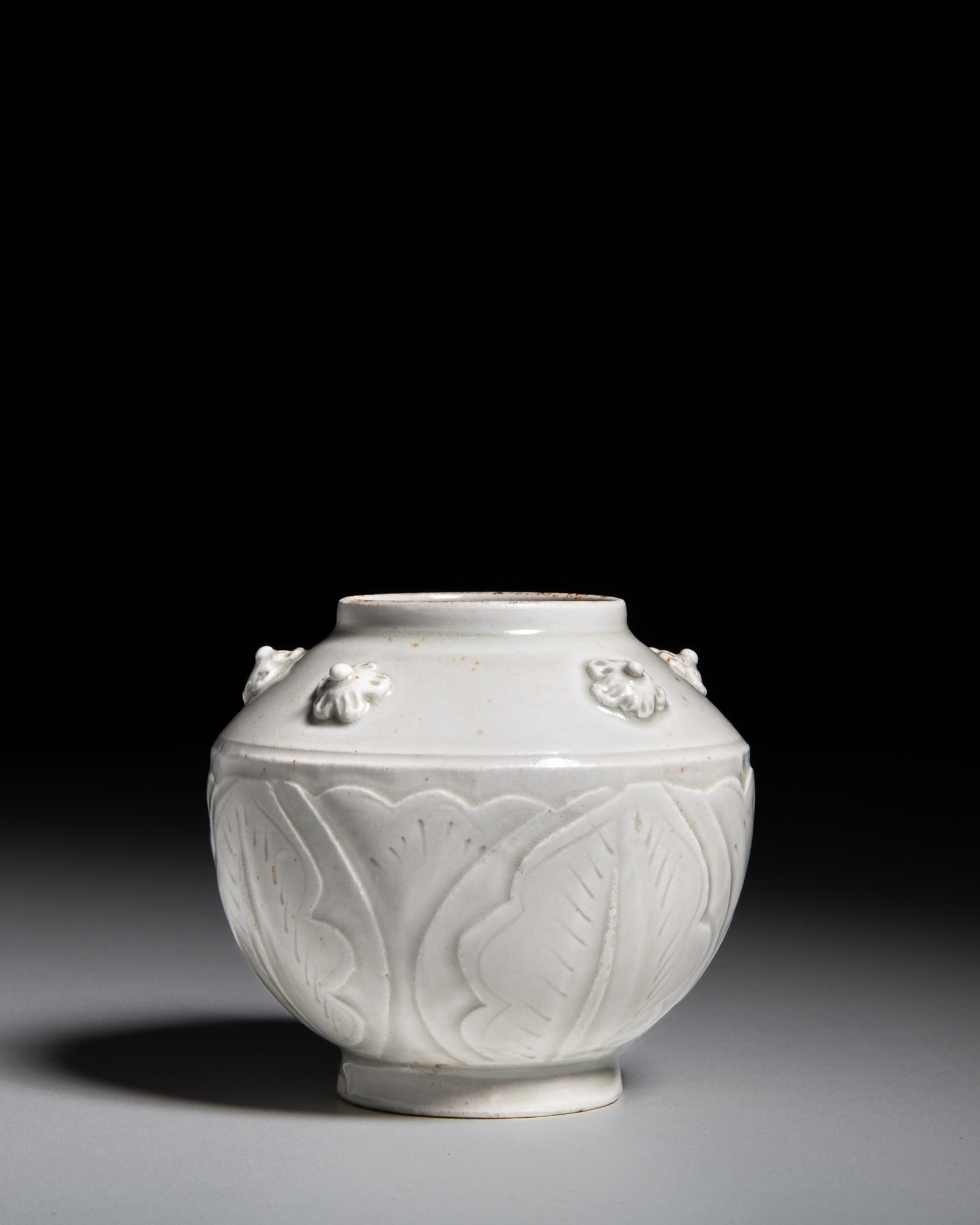 A SMALL WHITE-GLAZED JAR WITH CARVED LOTUS MOTIFS AND APPLIED FLORAL RELIEF DECORATION 仿 (1 of 2)