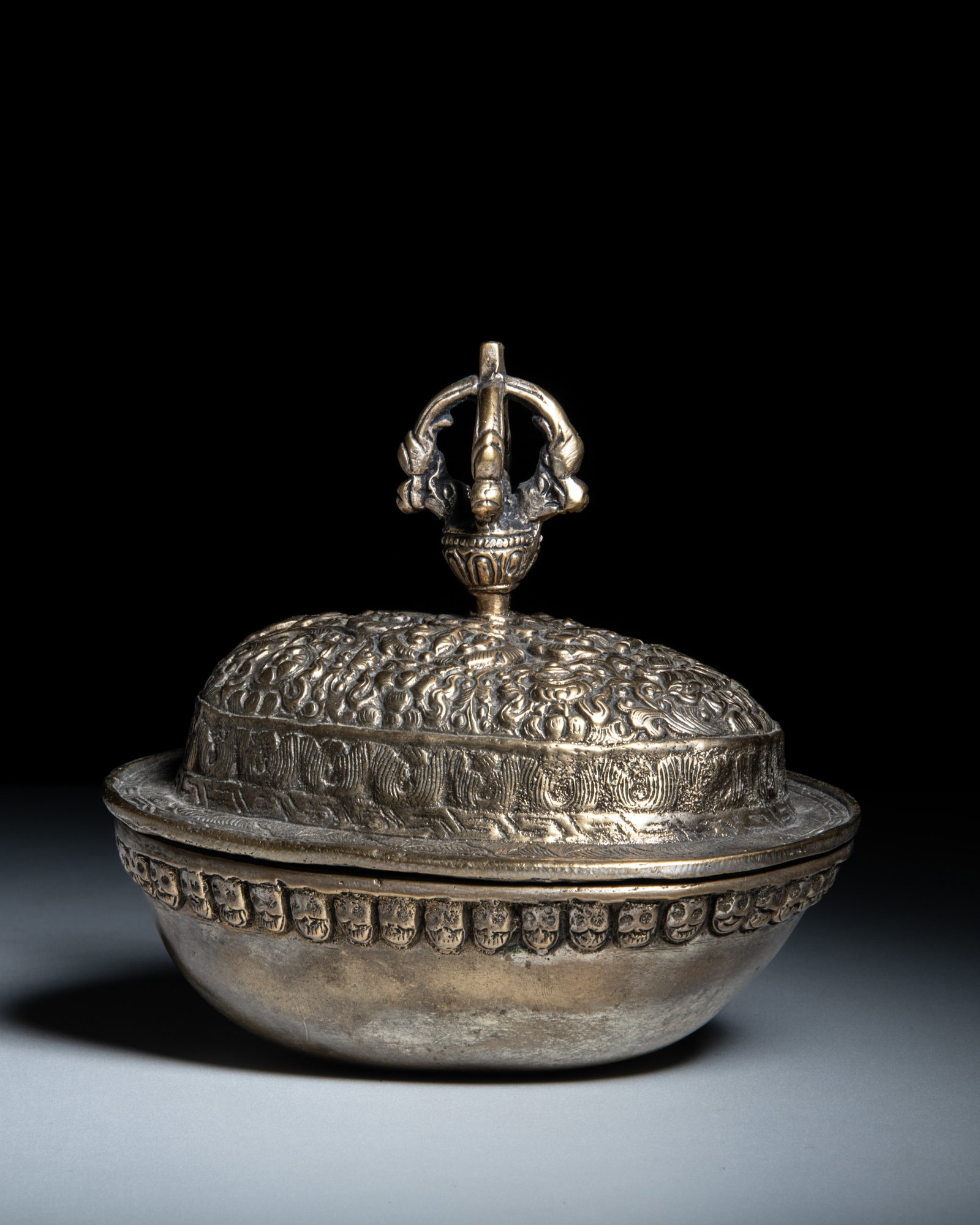 A FINE RITUAL COPPER SKULL BOWL (KAPALA) AND COVER WITH VAJRA FINIAL Tibet, early 20th century: A FINE RITUAL COPPER SKULL BOWL (KAPALA) AND COVER WITH VAJRA FINIAL Tibet, early 20th century of traditional form, with a smooth, aged interior reflecting its ritual use. The skull is encased in a fi