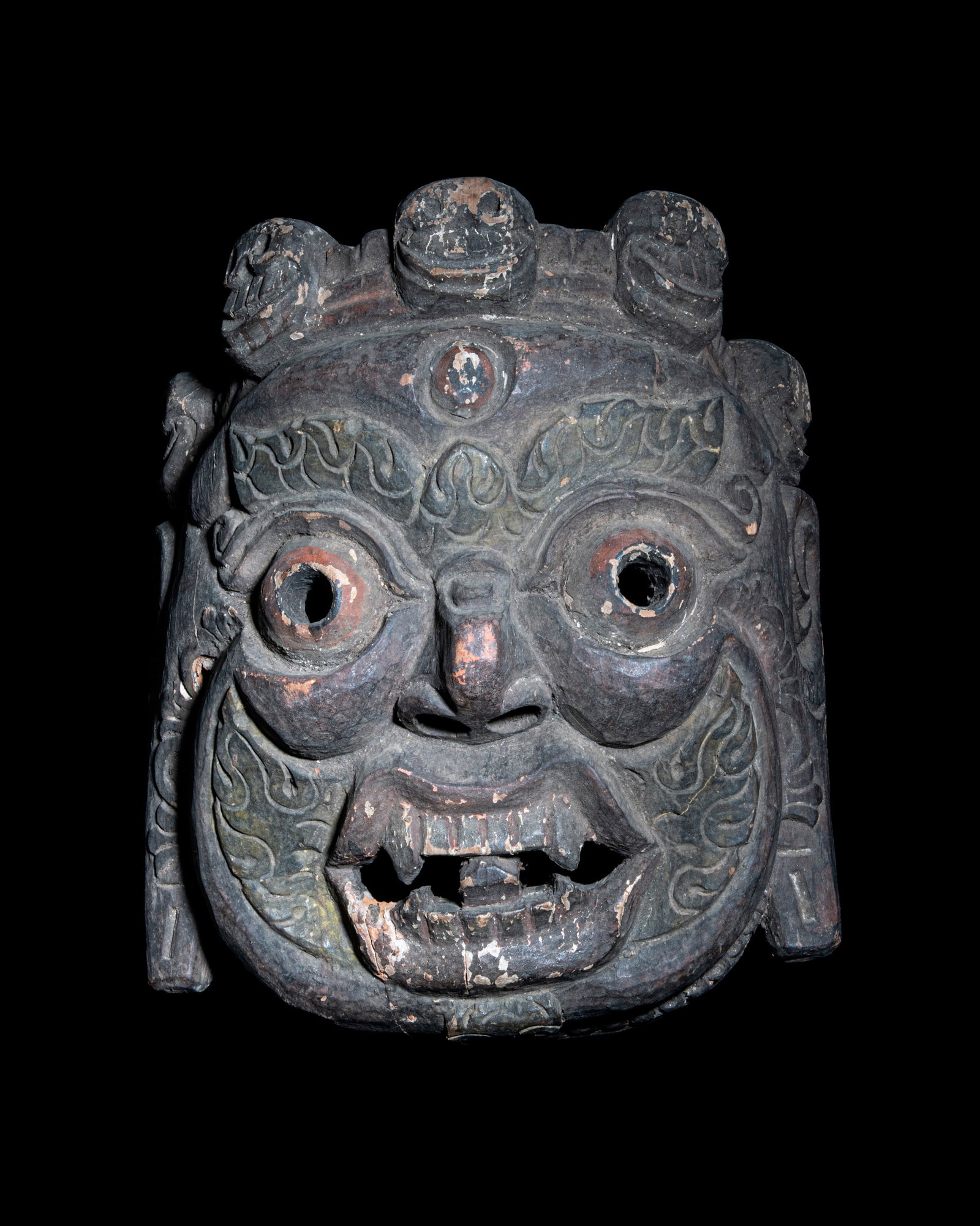 A CARVED WOOD RITUAL MASK OF A BLACK MAHAKALA WITH CITIPATTI CROWN Nepal, 20th Century. With: A CARVED WOOD RITUAL MASK OF A BLACK MAHAKALA WITH CITIPATTI CROWN Nepal, 20th Century. With traces of polychrome pigment H: 30.5 cm W: 29 cm Provenance: from the collection of a prominent former Euro