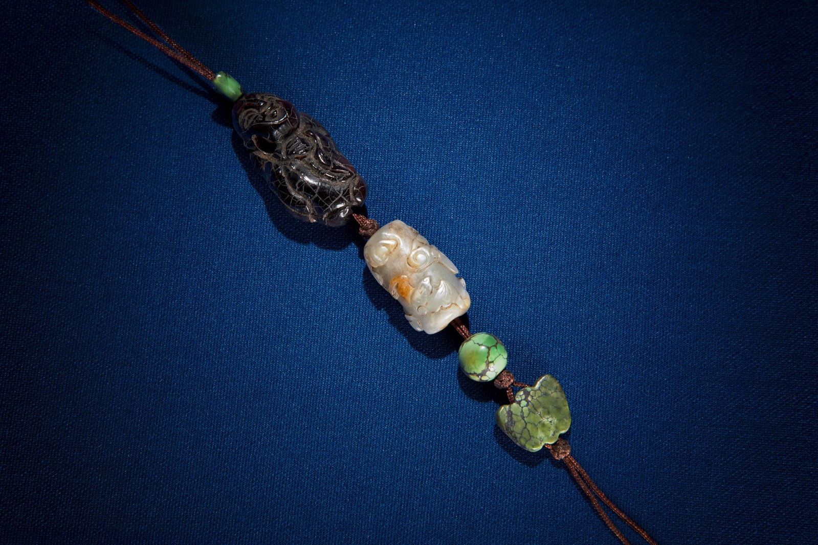 A PENDANT WITH CARVED AMBER, TURQUOISE AND JADE BEAD 清代 琥珀、: A PENDANT WITH CARVED AMBER, TURQUOISE AND JADE BEAD 清代 琥珀、青玉、松石雕挂坠一串 China, Qing dynasty