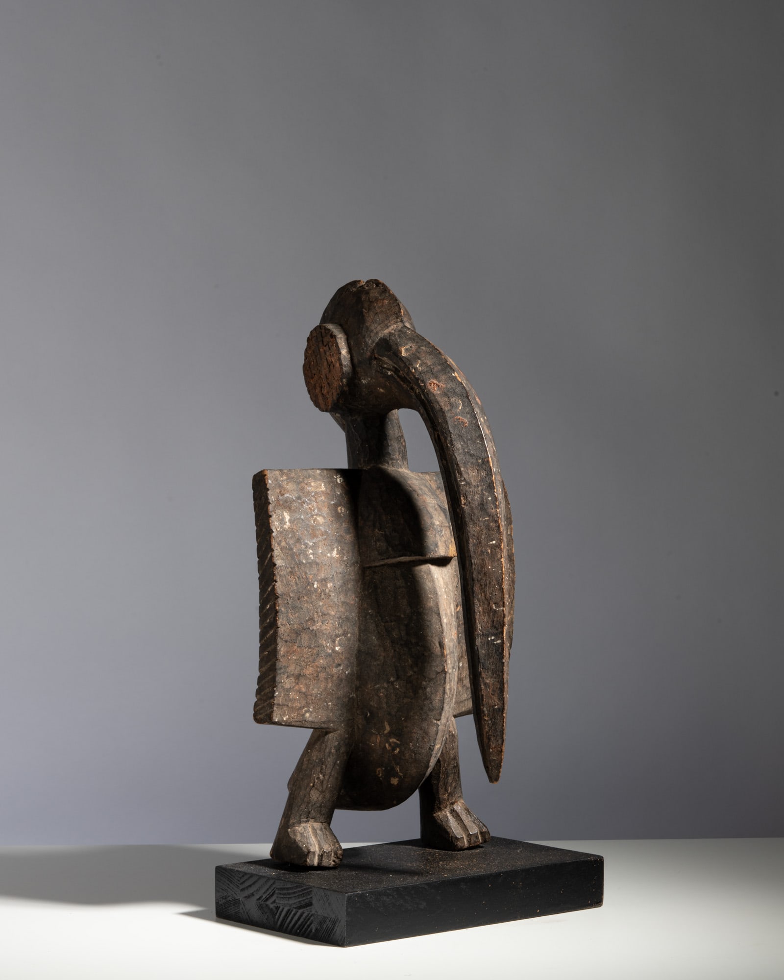A SENUFO FEMALE ANCESTRAL FIGURE Ivory Coast Wood This elegant and powerful ancestral female: A SENUFO FEMALE ANCESTRAL FIGURE Ivory Coast Wood This elegant and powerful ancestral female figure stands with an upright, dignified posture on a circular base. The stylized head is characterized by 