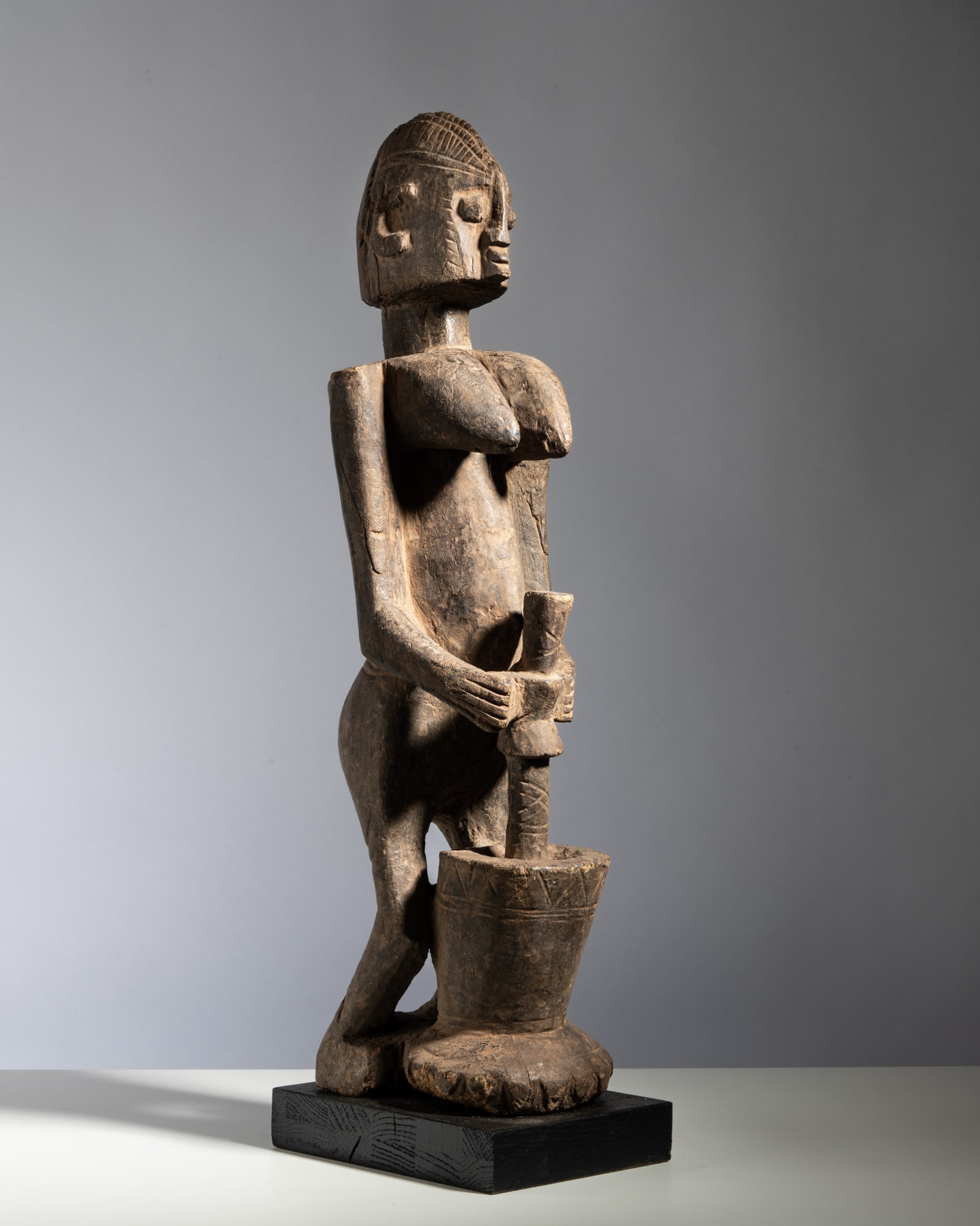 A LARGE DOGON FIGURE OF A WOMAN POUNDING FOOD Mali Wood This commanding and monumentally scaled: A LARGE DOGON FIGURE OF A WOMAN POUNDING FOOD Mali Wood This commanding and monumentally scaled tribal sculpture depicts a woman engaged in the ritual and domestic act of pounding millet or food, carv