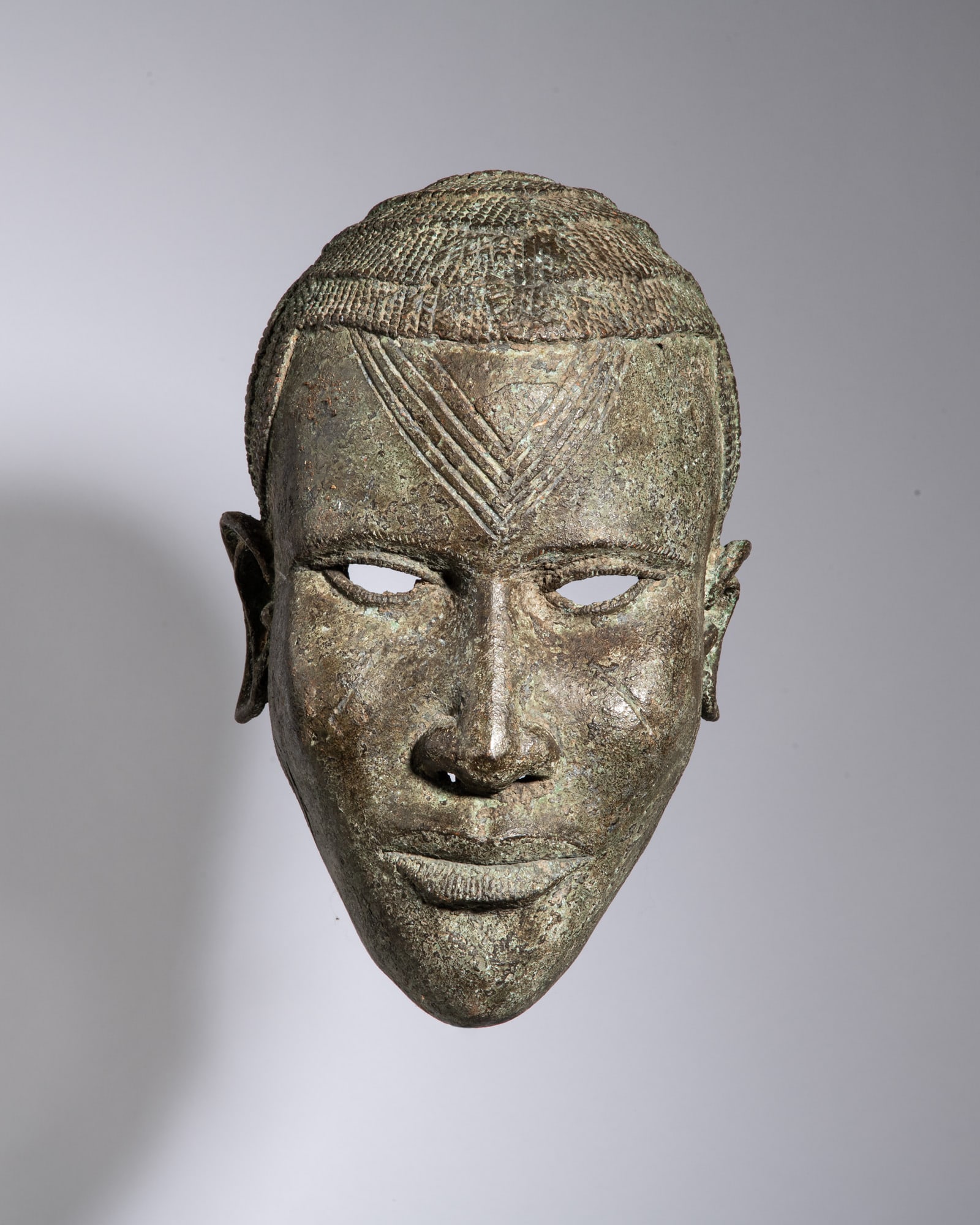 AN IFE BRONZE RITUAL MASK Ife Kingdom / Nigeria Bronze This cast bronze ritual mask exemplifies (1 of 3)