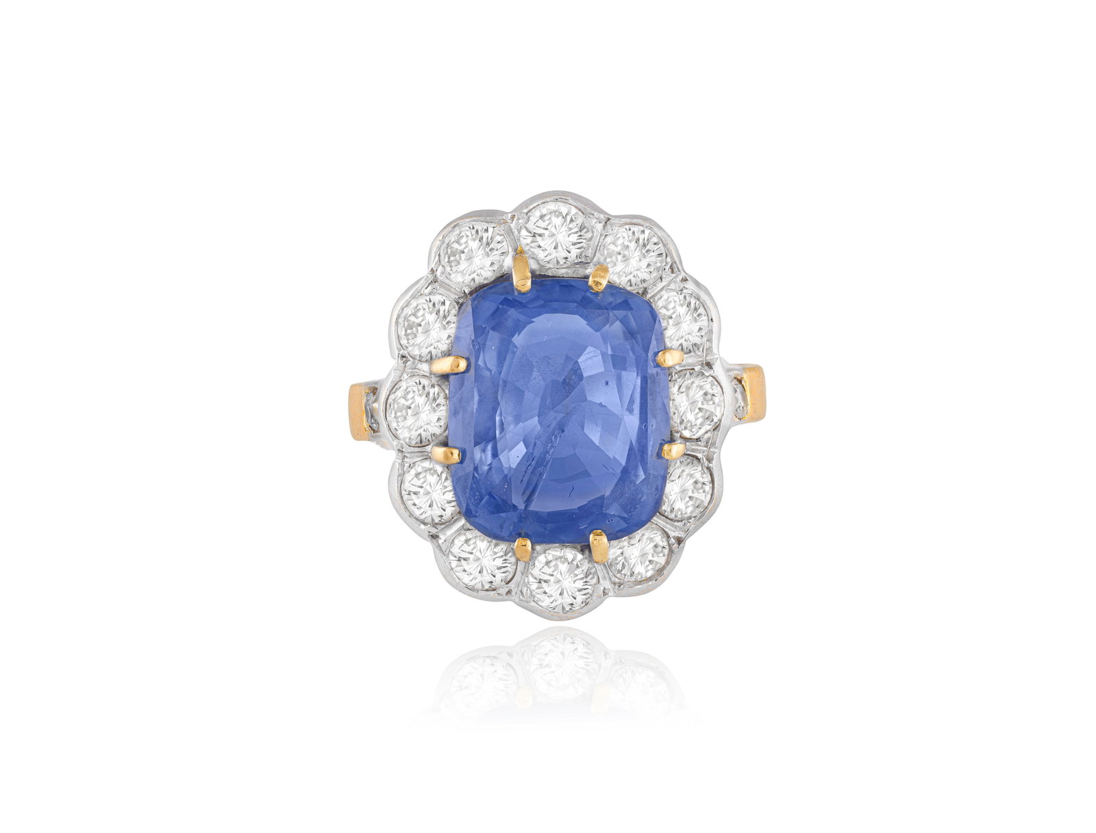 A SAPPHIRE AND DIAMOND CLUSTER RING The cushion-shaped sapphire weighing approximately 5.50cts,: A SAPPHIRE AND DIAMOND CLUSTER RING The cushion-shaped sapphire weighing approximately 5.50cts, within a brilliant-cut diamond surround and between similarly-cut diamond shoulders, mounted 18K gold, d
