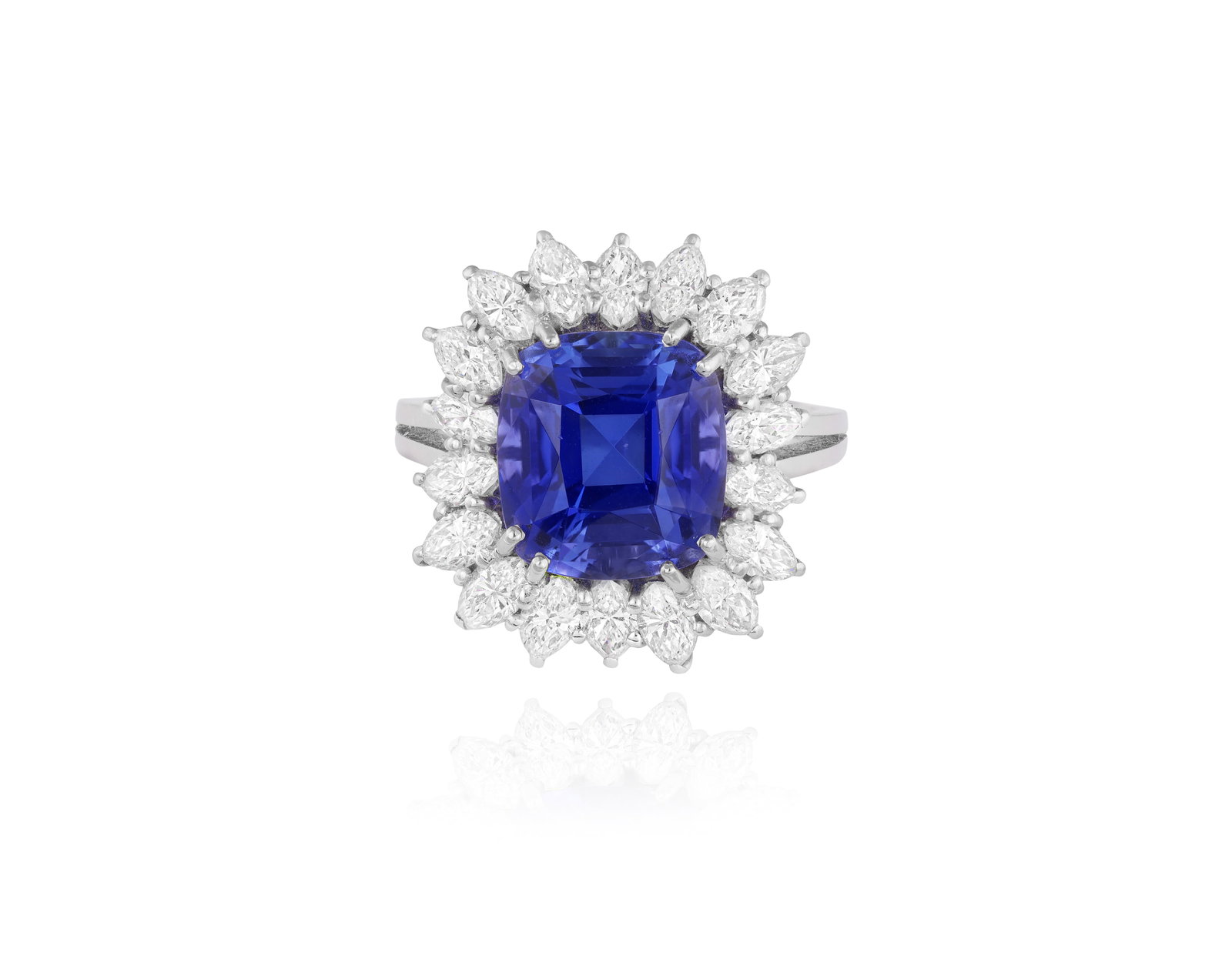 A TANZANITE AND DIAMOND DRESS RING Of ballerina cluster design, the square cushion-shaped tanzanite: A TANZANITE AND DIAMOND DRESS RING Of ballerina cluster design, the square cushion-shaped tanzanite weighing approximately 6.10cts, within a double four-claw setting, to an undulating surround of marq