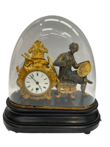 A 19th Century French figural mantel clock with a glass dome: A 19th Century French figural mantel clock with a glass dome and wooden oval base. A unique Gilted and patinated figure of an artist with a palette and a paint brush in hand. The clock has inscription