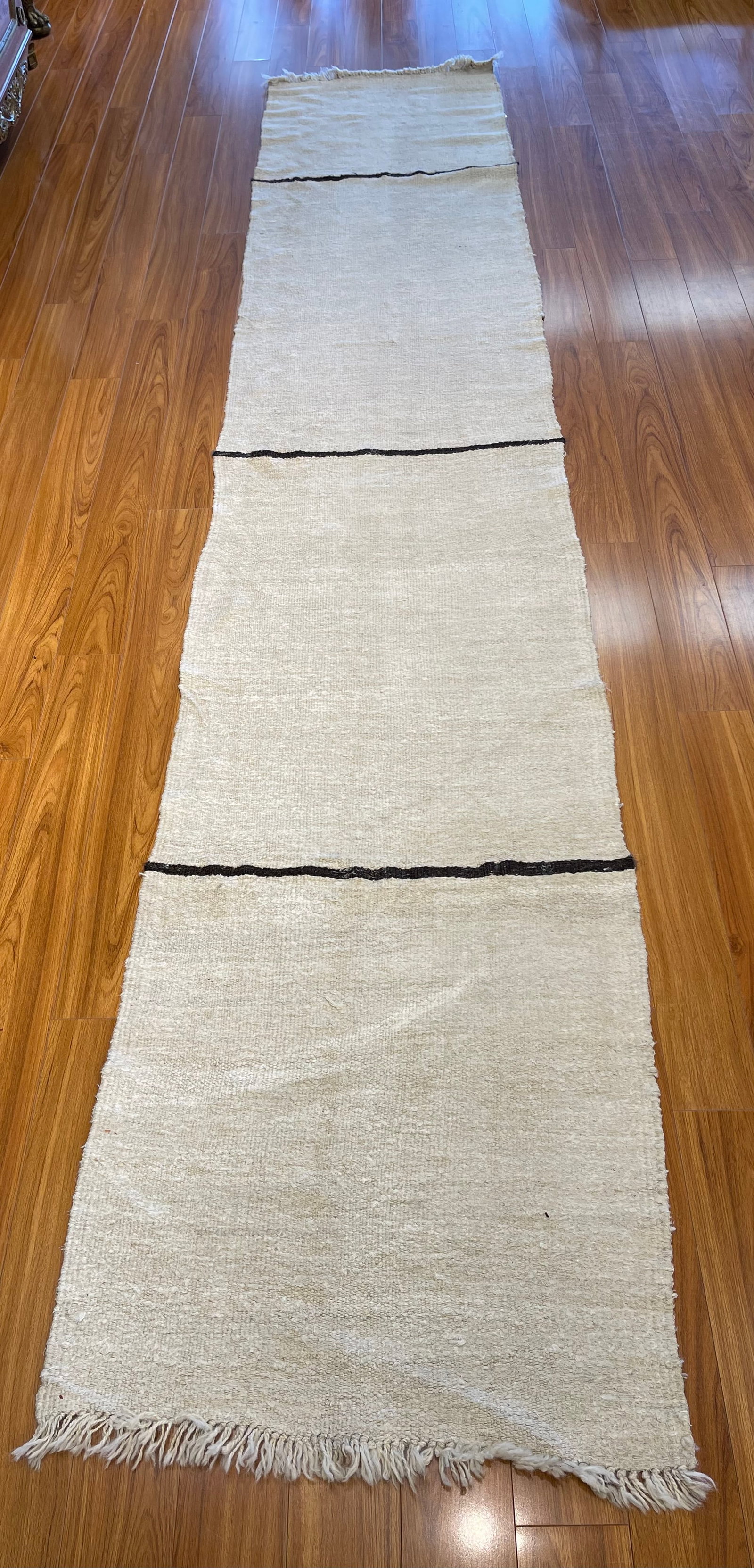 A handwoven Moroccan wool Runner: A handwoven Moroccan wool Runner measuring 2 feet 7 inches wide by 13 feet 4 inches long. A contemporary design flat woven runner wool rug.