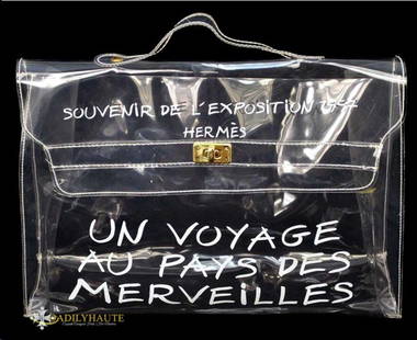 HERMES KELLY SOUVENIR DE L'EXPOSITION BAG: Hermes Clear Vinyl "Kelly" Bag with Souvenir de l'exposition 1997 Hermes with White Lettering "Un voyage Au Pay Des Merveilles" on front, top handle, gold-tone hardware twist & lock clasp through flap