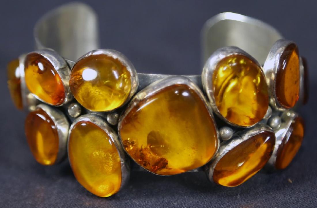 STERLING SILVER CABOCHON AMBER STONE BANGLE BRACELET: A STERLING SILVER LARGE YELLOW CABOCHON AMBER STONES SET IN A GEOMETRIC PATTERN BANGLE BRACELET. CUSTOM DESIGNED AND SIGNED M. GUERRO. PURCHASED AT ORNAMENTS OF SANTA FE, NM., IN 1995.