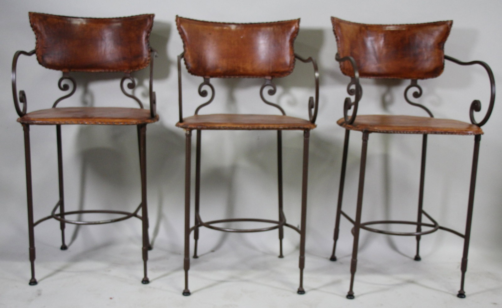 THREE HAMMERED IRON ROUND BACK BACK BARSTOOLS: LOT OF THREE HAMMERED IRON ROUND BACK BACK BARSTOOLS WITH LEATHER SEAT AND BACKS. Height: 39 in. by Width: 20 in. by Depth: 18