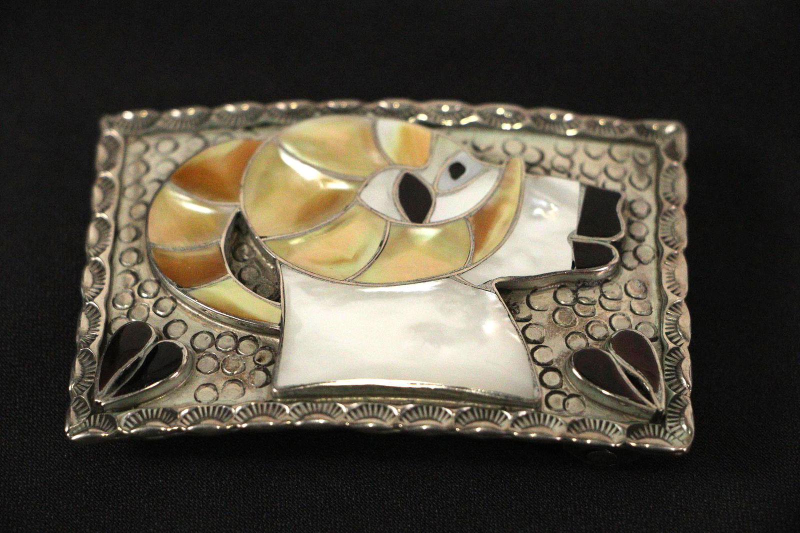SILVER RAMS HEAD MOTIF BELT BUCKLE: STERLING SILVER BELT BUCKLE WITH A "RAMS HEAD" MOTIF. THIS 3in BY 2in BUCKLE IS CUSTOM MADE BY BOBBY & CORRAINE SHACK OF ZUNI, NEW MEXICO. THIS BUCKLE HAS AN ABALONE RAISED SURFACE THAT GIVES IT A 3-D