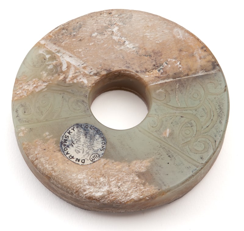 CHINESE QING CARVED JADE BI DISK: CHINESE QING CARVED JADE BI DISK, CARVED TO DEPICT THE FACE OF THE BEAST AND A DRAGON, RAISED ON A ROSEWOOD STAND. PROVENANCE FROM THE DN RODINSKY COLLECTION. Height: 3 in. by Width: 3 in. by Depth: 3