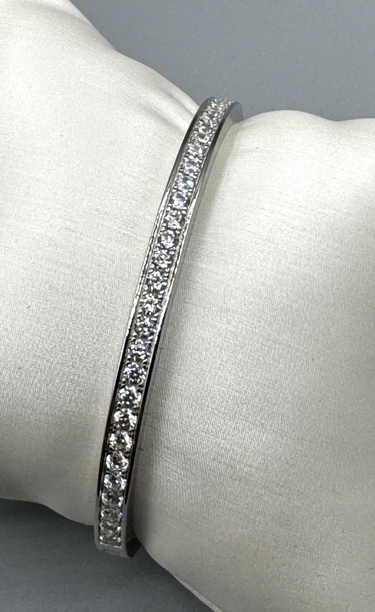 WHITE SAPPHIRE STERLING SILVER BANGLE BRACELET: WHITE SAPPHIRE STERLING SILVER BANGLE BRACELET. Height: 2 in. by Width: 2.5 in. by Depth: 3/16 in.