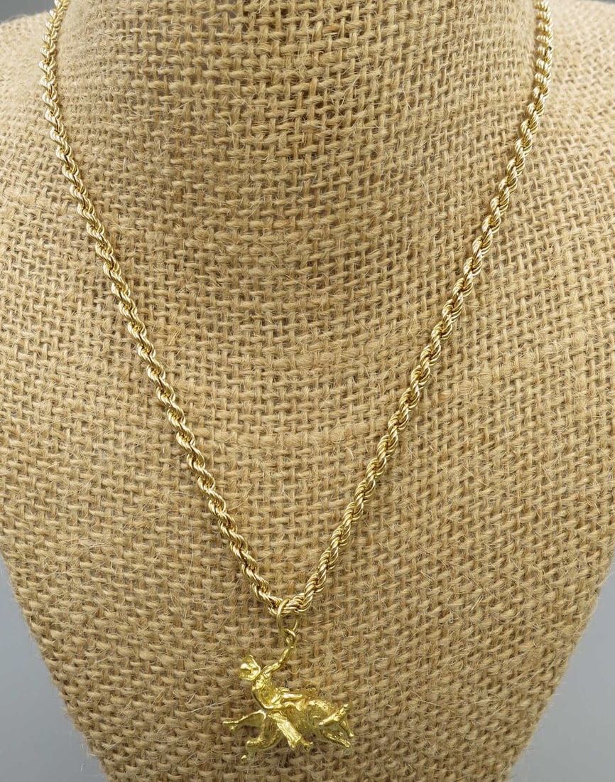 GOLD BULL RIDER ON HORSEBACK PENDANT ON CHAIN: GOLD BULL RIDER ON HORSEBACK PENDANT ON 16" CHAIN. Height: 1 in. by Width: 1 in. by Depth: 5/8 in.