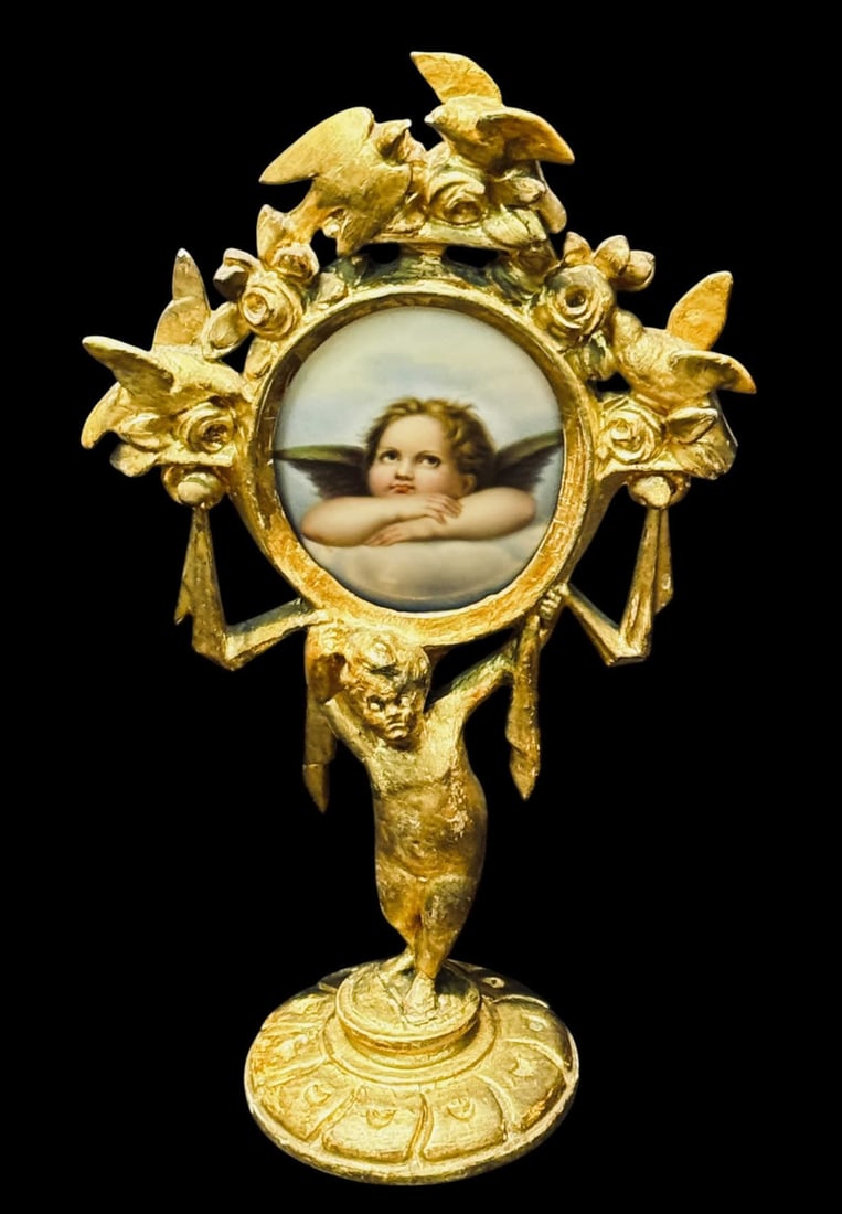 GILDED AND CARVED FRAME WITH ENAMEL PUTTI: GILDED AND WOOD CARVED FRAME WITH HAND PAINTED ENAMEL PUTTI PLAQUE