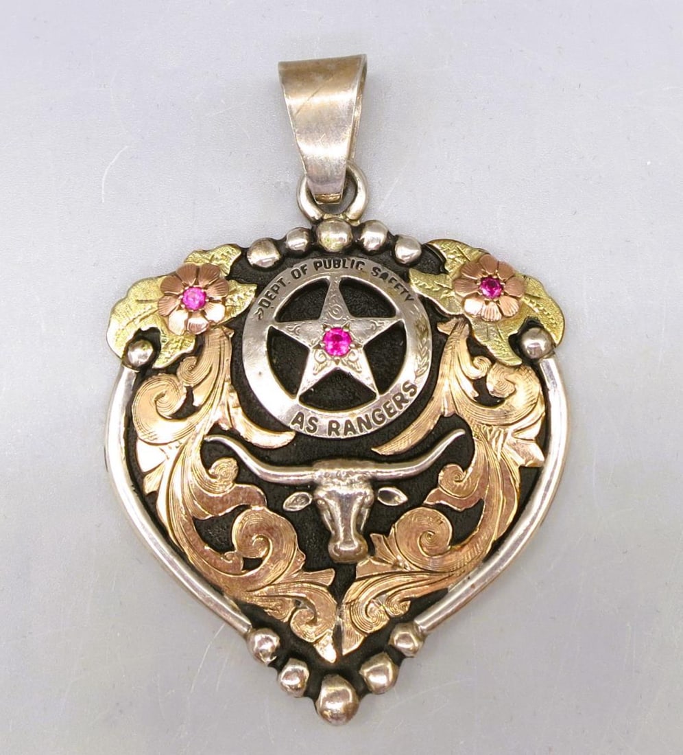 WESTERN-STYLE HEART PENDANT WITH A TEXAS LONGHORN: WESTERN-STYLE STERLING SILVER HEART PENDANT WITH A TEXAS LONGHORN STEER WITH A PINK TOURMALINE & GOLD-TONE FLORAL FILIGREE DETAILING. 39 GRAMS T.W. Height: 2.75 in. by Width: 2 in. by Depth: .25 in.