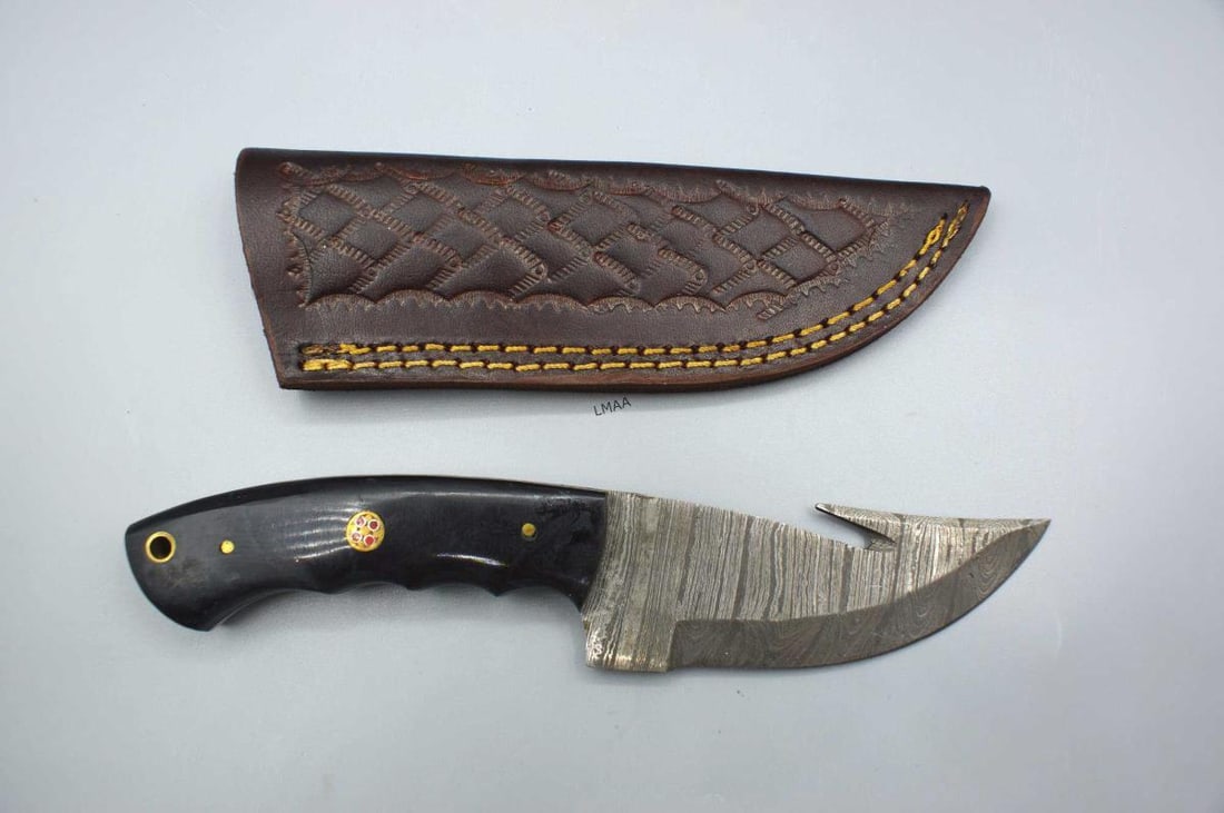 HANDMADE DAMASCUS STEEL FIXED-BLADE KNIFE: HANDMADE DAMASCUS STEEL FIXED-BLADE KNIFE FEATURING A GUT HOOK FOR SKINNING GAME AND A DISTINCTIVE WOODEN HANDLE.