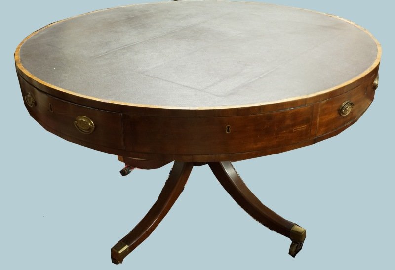 AMERICAN DRUM TABLE, CIRCA 1810: AMERICAN DRUM TABLE , CIRCA 1810. THE ROUND TOP WITH EBONY STRINGING AND INSET BURGUNDY LEATHER FRIEZE ALTERNATING WITH FOUR WORKING AND FOUR FAUX DRAWERS, EACH WITH FEDERAL BRASS PULLS, THE BACK PLAT