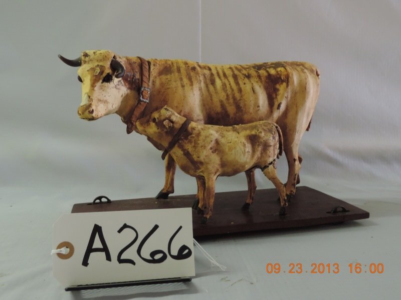 Cow and calf mounted on wheels with leather colla.: Cow and calf mounted on wheels with leather collars. They are on a wire frame with hide over them. Calf missing a leg. Cow’s neck split.