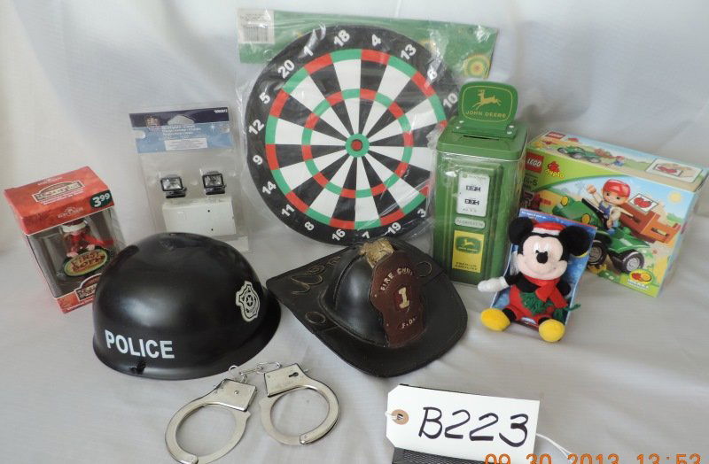 Police hat and handcuffs, fireman’s hat bank, Mick: Police hat and handcuffs, fireman’s hat bank, Mickey Pals, “Mom’s first born ornament, Lego Duplo Farm Bike, John Deere bank (gas pump), Dart Board, mini spot light. B223