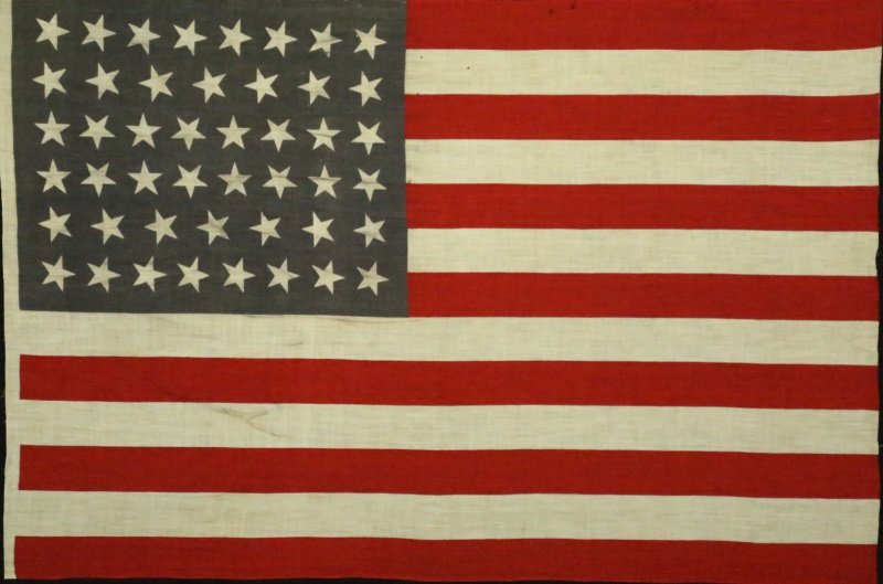 OKLAHOMA STATEHOOD FLAG: "OKLAHOMA STATEHOOD FLAG". MEDIUM: ORIGINAL 46 STAR AMERICAN PARADE FLAG PRINTED ON COTTON. 46 STARS ON A DUSTY BLUE CANTON, 1907-1912, OKLAHOMA STATEHOOD, SCATTERED STAR POSITIONING. THE CANTON HAS F