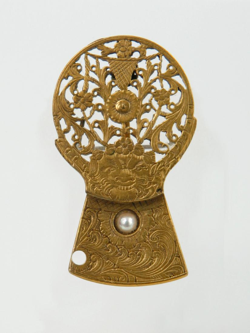 Brosche, Spindelkolben: 122 Brosche, Spindelkolben Gold und Perleneinlage. H 3,7 cm. B 2,1 cm. Provenienz: Nachlass Denise David, Zuerich. Brosche aus einem Spindelkolben mitdurchbrochenem, floralen Motiv und karikiertem Ges