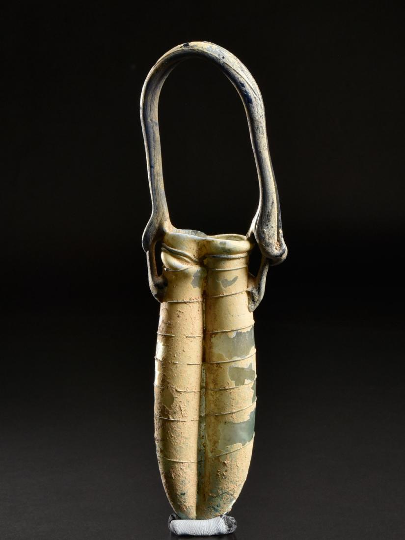 A Double Roman Toilet Bottle: DOPPELSALBFLASCHE Römisch, Östliches Mittelmeergebiet, 4. Jh. n. Chr. Ohne Sockel / without base Glas. H 18,4 cm. CHF 225 / 450 EUR 193 / 387