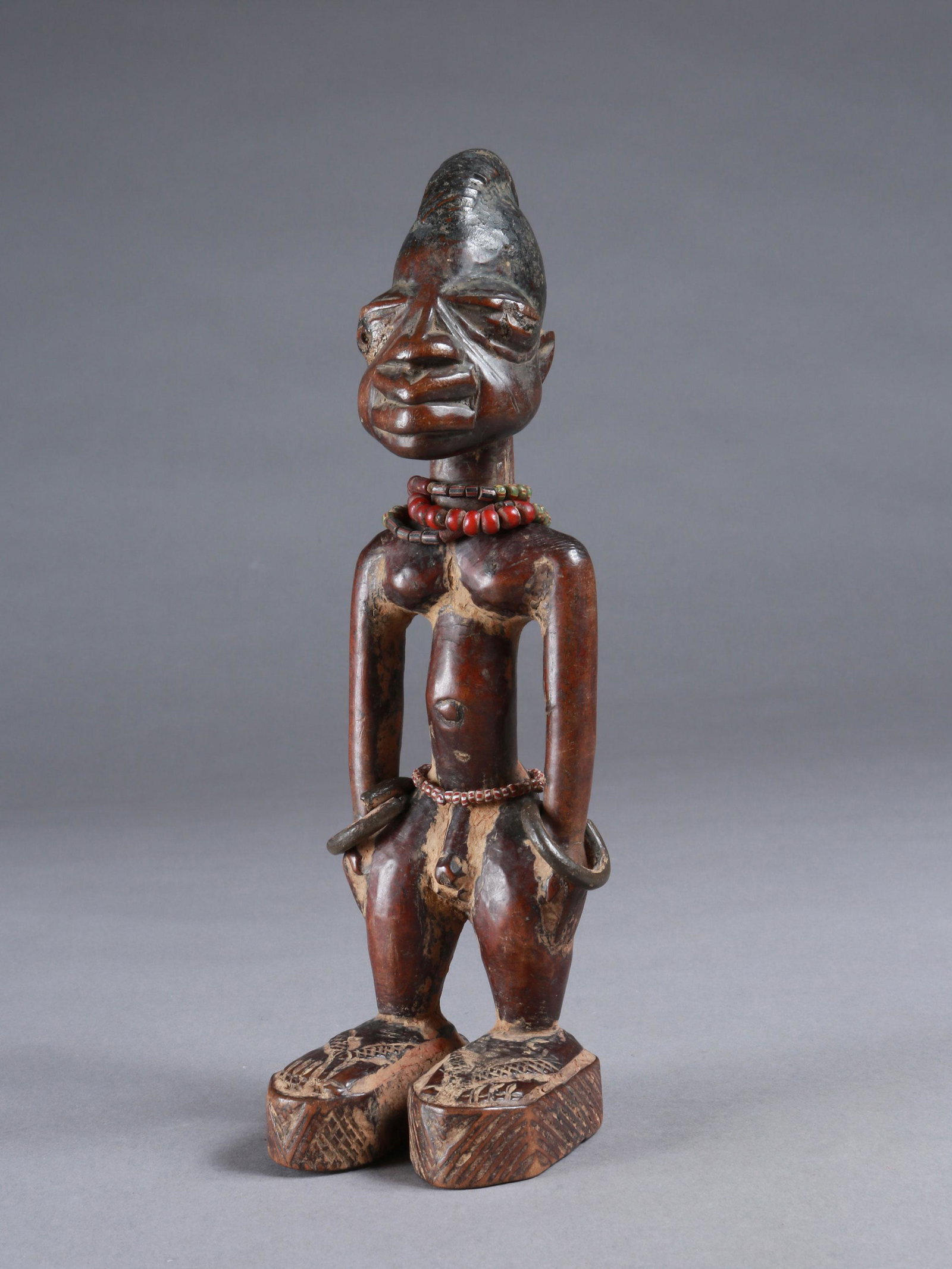 A Yoruba Twin Figure, "ere ibeji": Zwillingsfigur, "ere ibeji" Yoruba, Nigeria Ohne Sockel / without base Holz, Gelbguss, Glasperlen. H 25,5 cm. Provenienz: Walter Häusler, Thurgau. 1960er Jahre in Nigeria erworben. Über Zwillinge wu