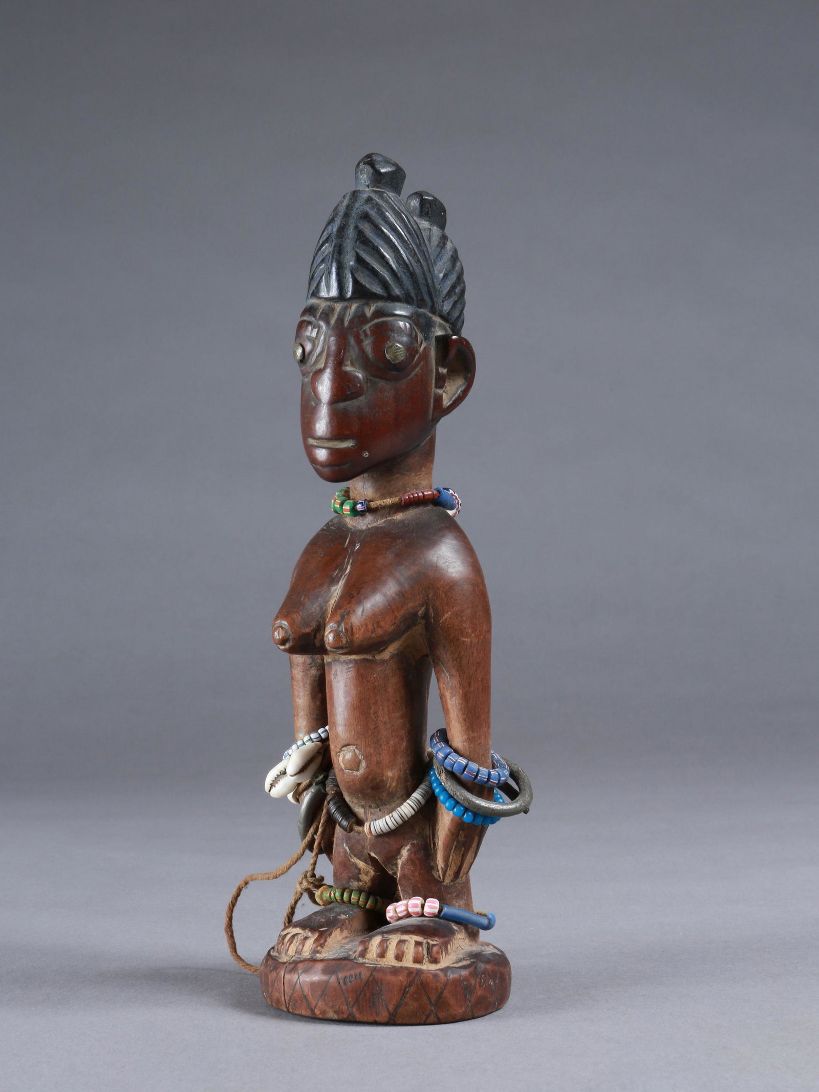 A Yoruba Twin Figure, "ere ibeji": Zwillingsfigur, "ere ibeji" Yoruba, Nigeria Ohne Sockel / without base Holz, Glasperlen, Kaurischnecken. H 25 cm. Provenienz: Walter Häusler, Thurgau. 1960er Jahre in Nigeria erworben. Über Zwilling
