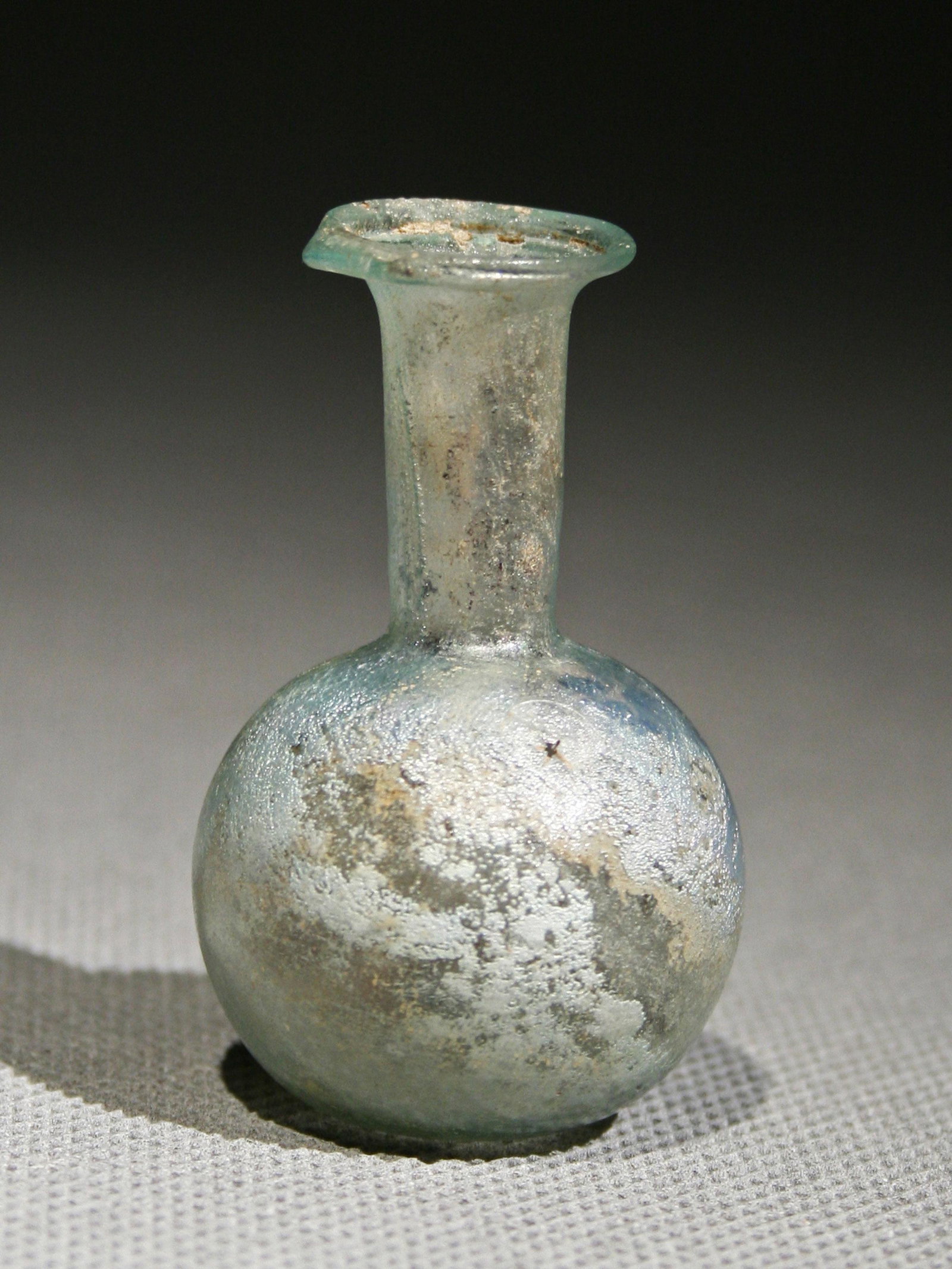 A Roman Bottle: FLÄSCHCHEN Römisch, Östliches Mittelmeergebiet Ohne Sockel / without base Glas. H 5,5 cm. Provenienz: Kunstmarkt Deutschland (2007). 3. - 4. Jh. n. Chr. Feines Loch in der Wandung / A minor lacuna 