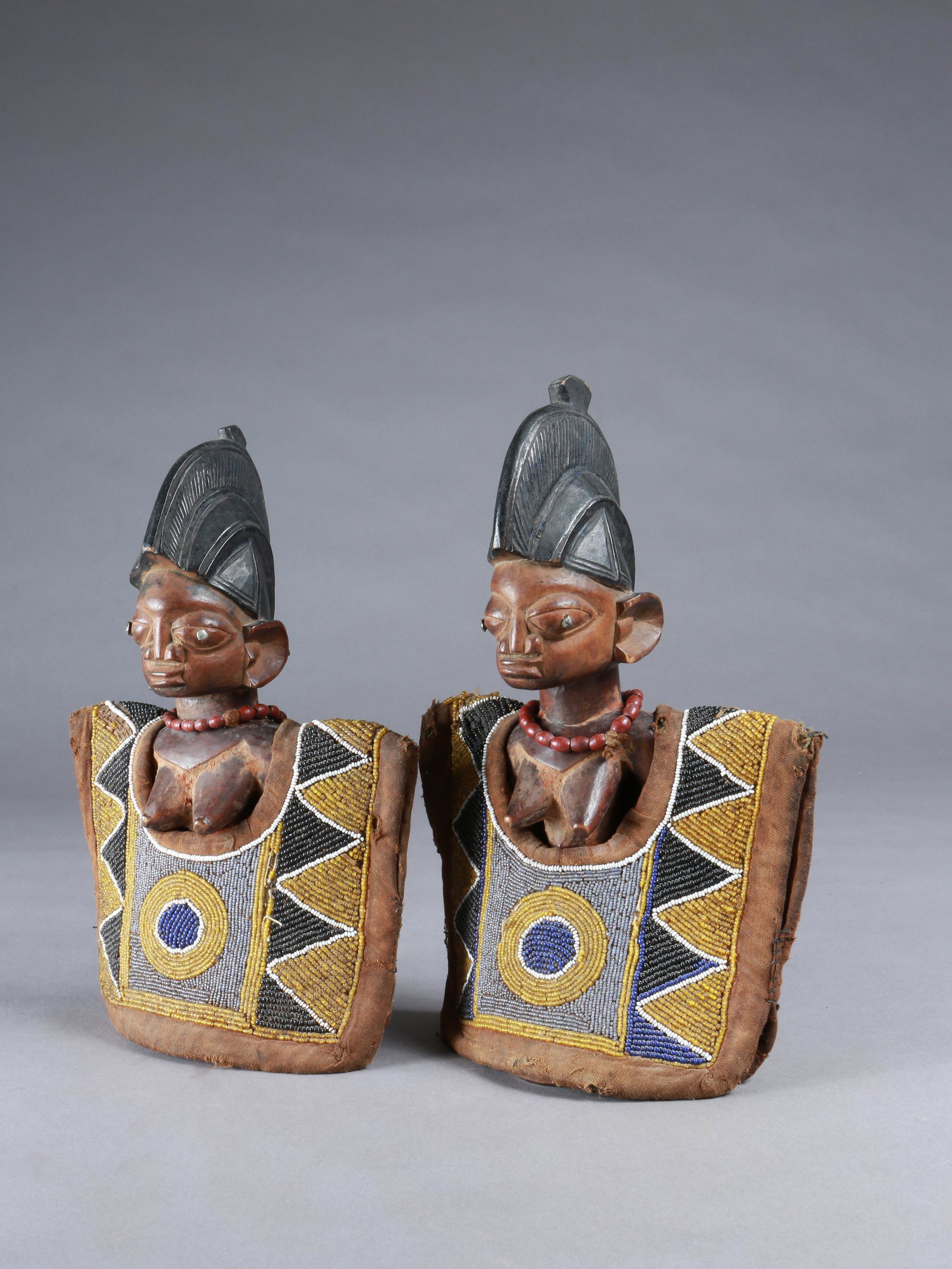 A Yoruba Pair of Twin Figures, "ere ibeji": Zwillingsfigurenpaar, "ere ibeji" Yoruba, Nigeria Ohne Sockel / without base Holz, Textil, Glasperlen. H 31 und 33 cm. Provenienz: Walter Häusler, Thurgau. 1960er Jahre in Nigeria erworben. Über Zwi