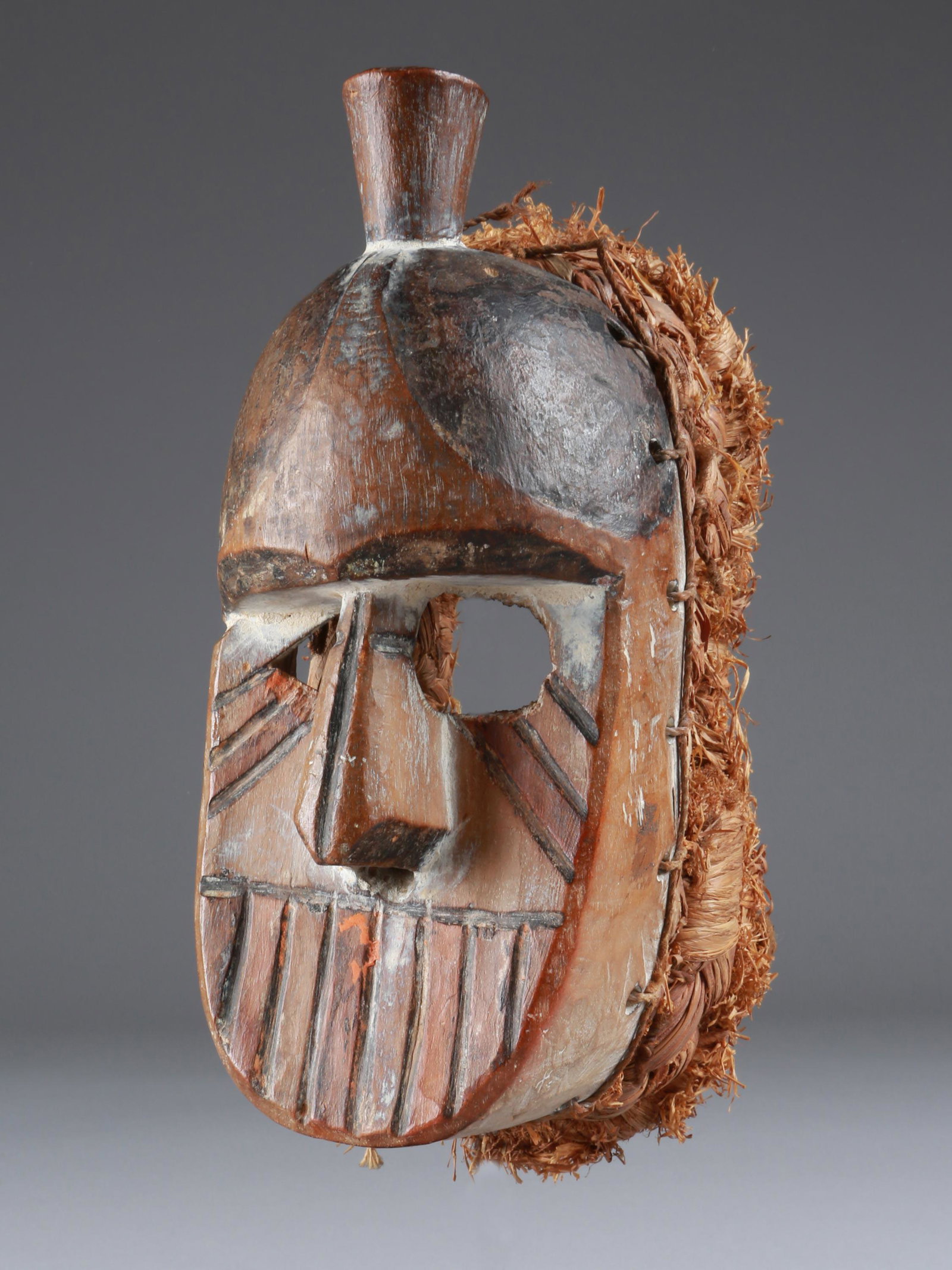 An Igbo-Afikpo Mask: Maske Igbo-Afikpo, Nigeria Ohne Sockel / without base Holz, Raphia. H 20 cm. Provenienz: Helmut und Marianne Zimmer, Zürich. CHF 200 / 400 EUR 172 / 344