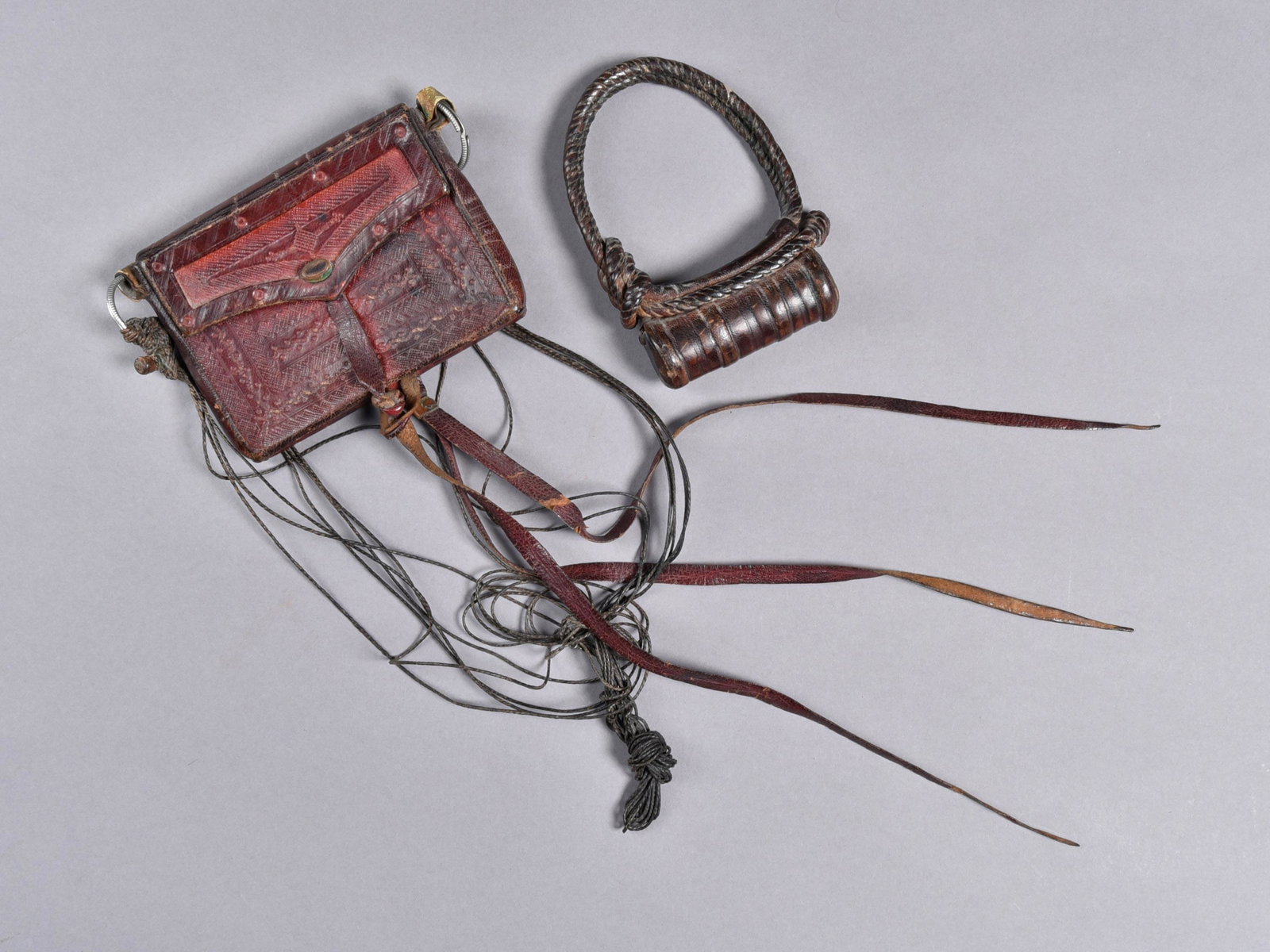 A Haussa Leather Bag and Armlet: Täschchen und Armschmuck Hausa, Kamerun, Nigeria Ohne Sockel / without base Leder. H Armreif 12 cm. B Tasche 13 cm. Provenienz: Helmut und Marianne Zimmer, Zürich. CHF 20 / 40 EUR 17 / 34