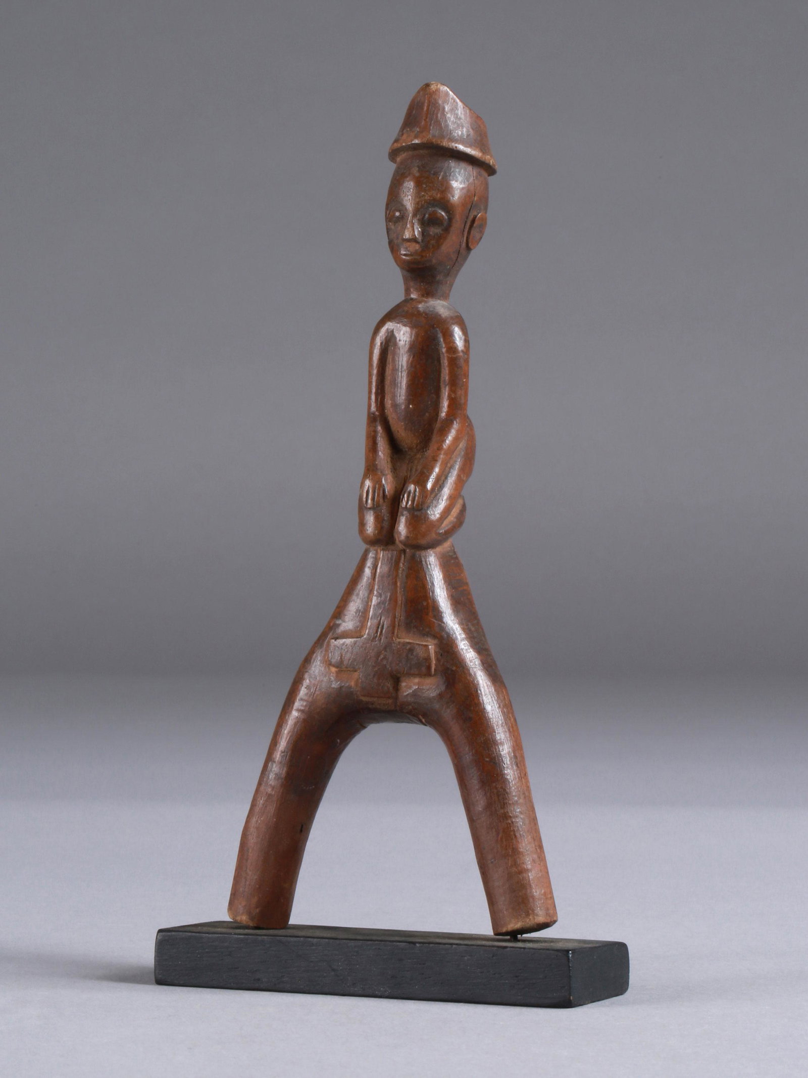 A Baule Slingshot, "potomowaka": Steinschleuder, "potomowaka" Baule, Côte d’Ivoire Mit Sockel / with base Holz. H 18,5 cm. Provenienz: Privatsammlung, Paris. Die Verbindung von Nützlichem und Schönem ist ein zentrales Anliegen d