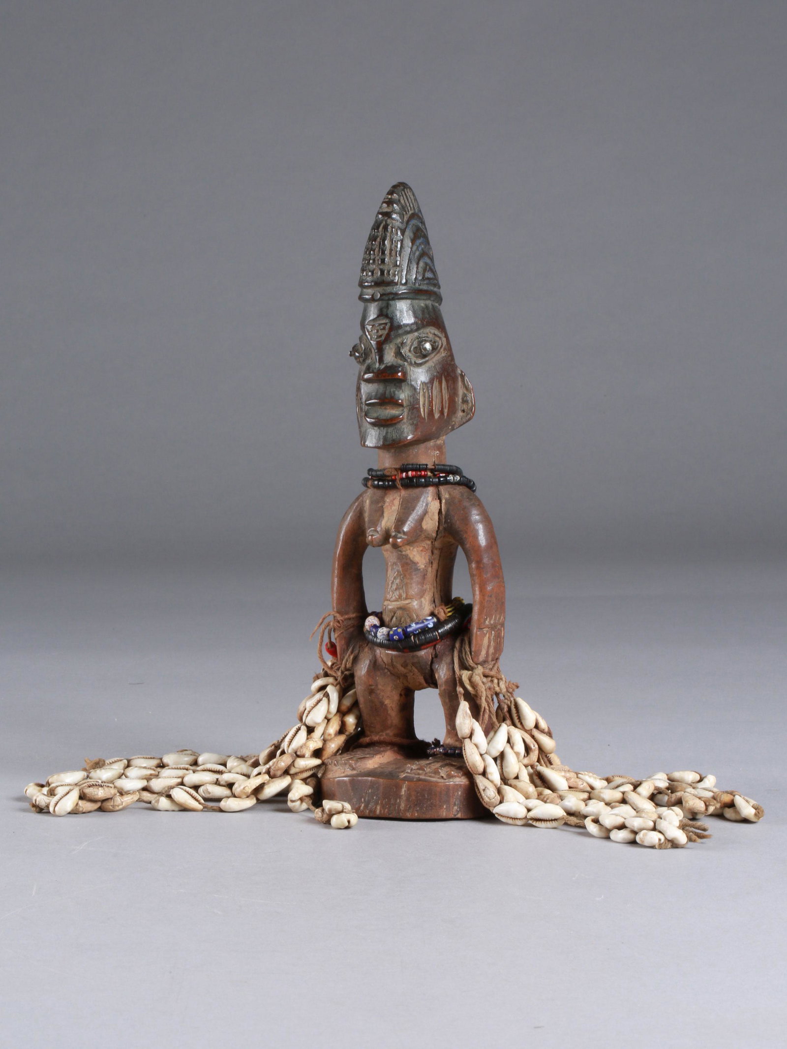 A Yoruba Twin Figure, "ere ibeji": Zwillingsfigur, "ere ibeji" Yoruba, Nigeria Ohne Sockel / without base Holz, Glasperlen, Kaurischnecken. H 27 cm. Provenienz: Martin Gross (1922-2017), Biel (erworben am 07.06.1975). Über Zwillinge w