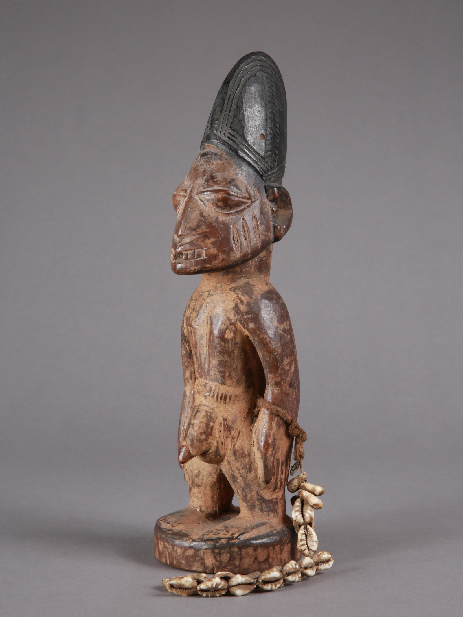 A Yoruba Twin Figure, "ere ibeji": Zwillingsfigur, "ere ibeji" Yoruba, Nigeria Ohne Sockel / without base Holz, Kaurischnecken. H 31 cm. Provenienz: Hans-Joachim Struck (1934-2016), 1980er Jahre in Nigeria erworben. Über Zwillinge