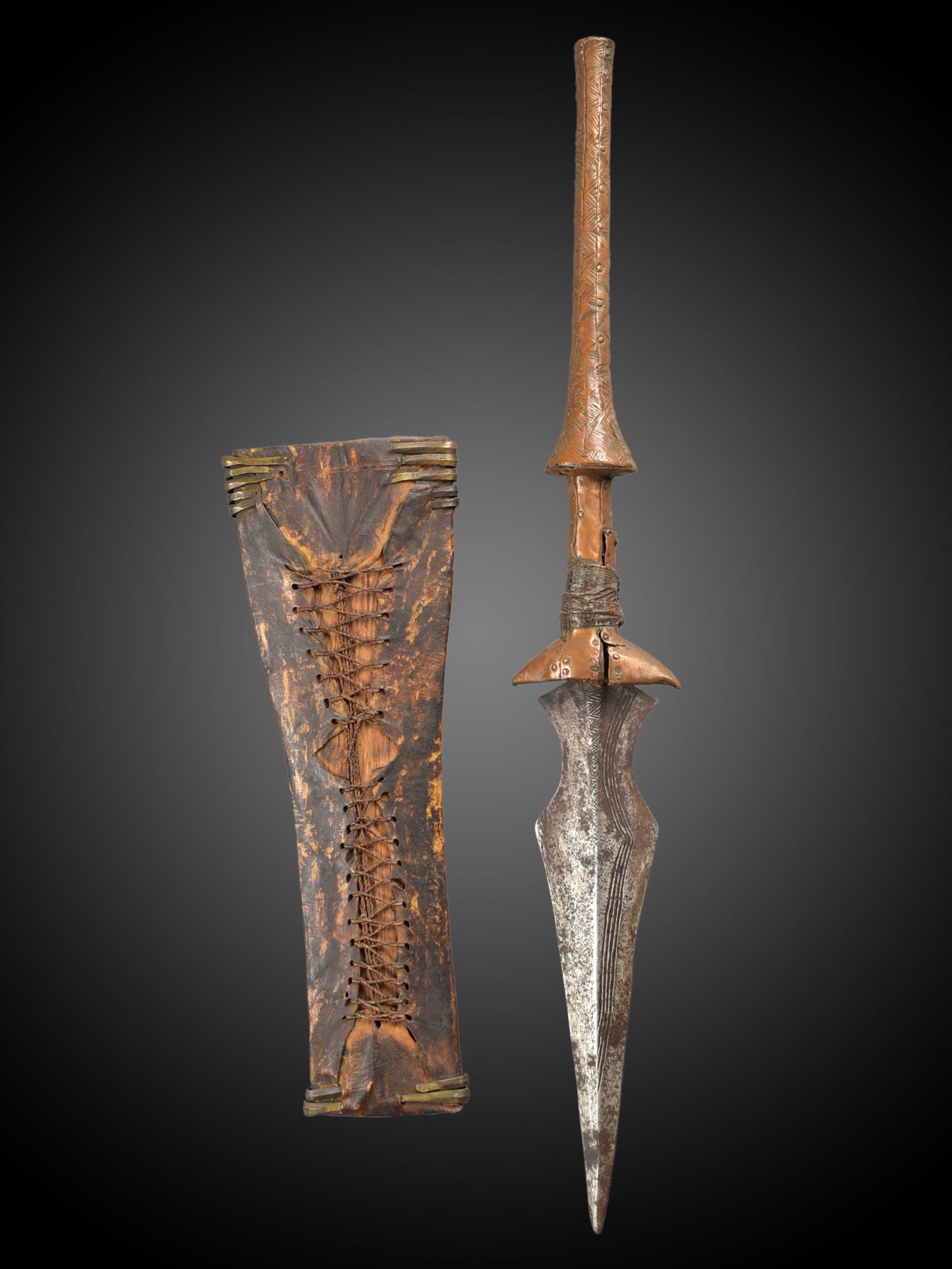 A Tetela Dagger with Sheath: Dolch mit Scheide Tetela, Sungu, Kusu, DR Kongo Ohne Sockel / without base Holz, Kupfer, Eisen, Leder, Bronze. H 57,5 cm. Provenienz: Helmut (1931-2021) und Marianne Zimmer, Zürich. Zeremonialwaf