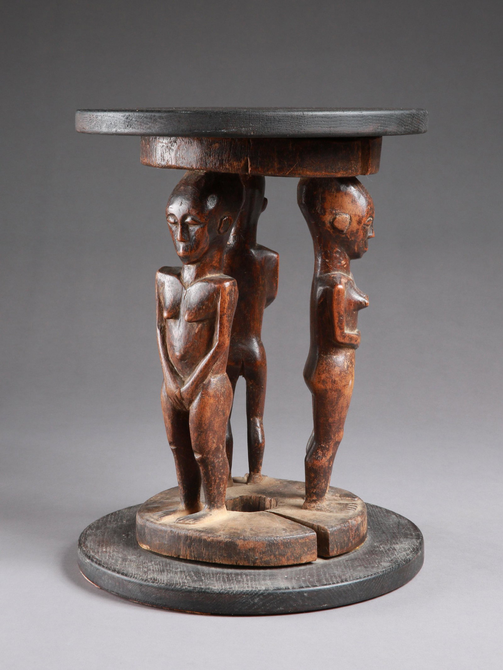 A Kamba Seat with three Figures: Sitz mit drei Figuren Kamba (?), Kenia Mit Sockel / with base Holz. H mit Sockel: 38,5 cm. / Objekt: 34 cm. Provenienz: - lt. mündl. Bestätigung: Galerie Walu, Basel (vor 1968). - Jeff Somme
