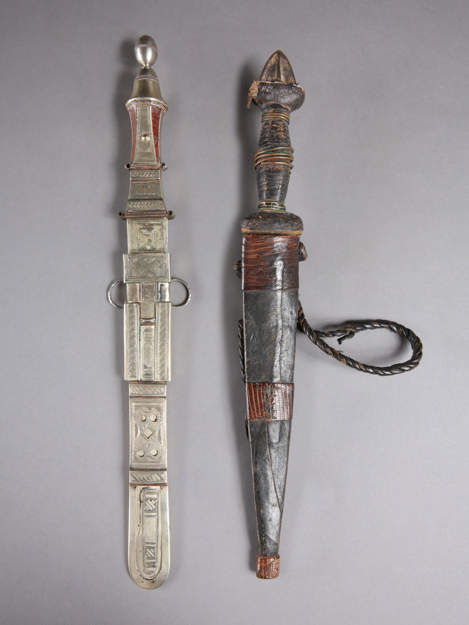 2 Tuareg Daggers with Sheath: 2 Dolche mit Scheiden Tuareg, Sahelzone Ohne Sockel / without base Silber, Holz, Leder. L 36 - 38,5 cm. Provenienz: Schweizer Privatsammlung, Basel. Zeremonialwaffen zeichnen sich durch sorgfälti