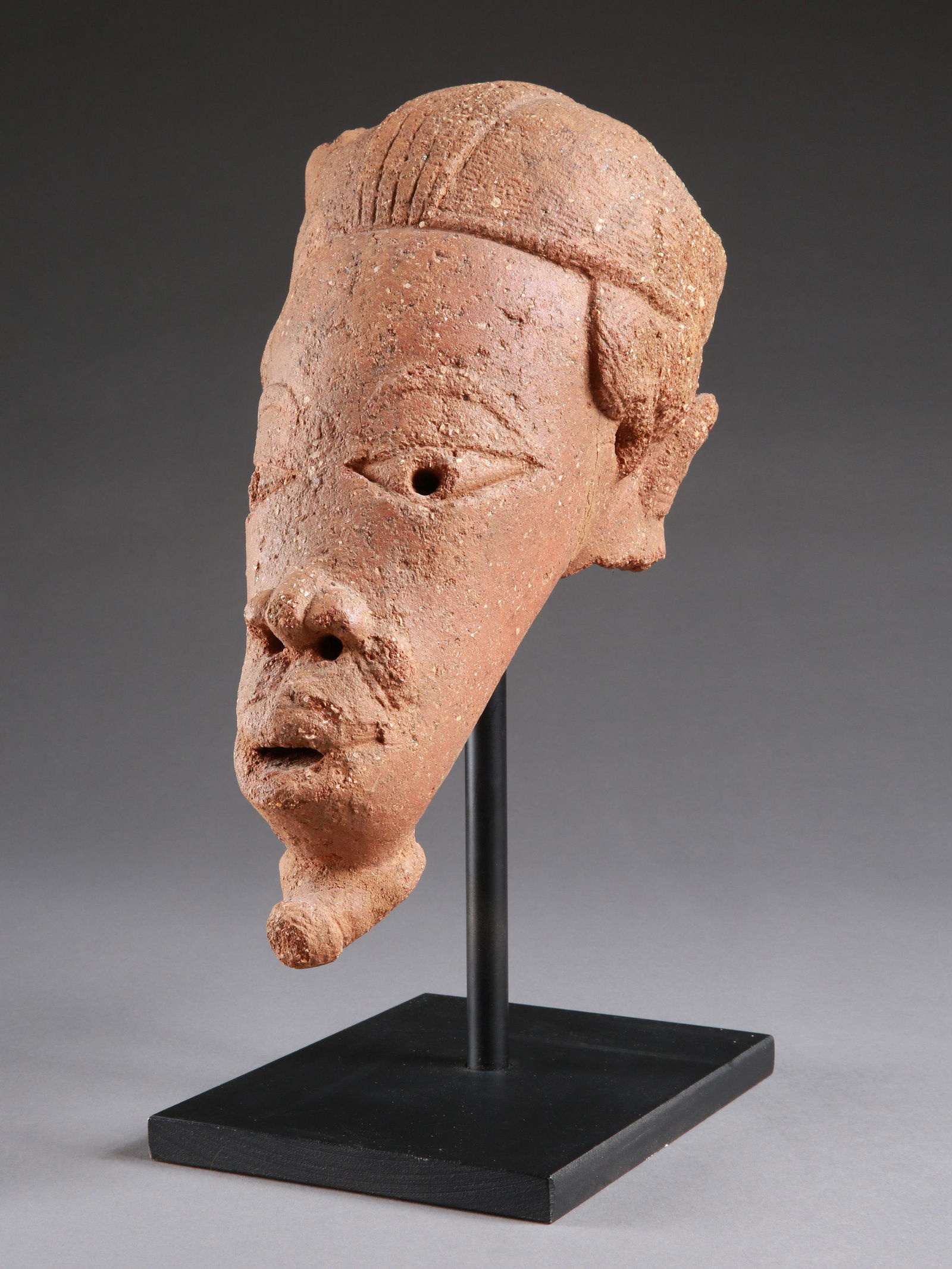 A Nok Head: Terrakotta-Kopf Nok, Nigeria Mit Sockel / with base Terrakotta. H 30 cm. Provenienz: - Galerie Walu, Zürich (vor 2000). - Schweizer Nachlass, Wallis. Thermolumineszenz-Altersbestimmung: 2000 Jahr