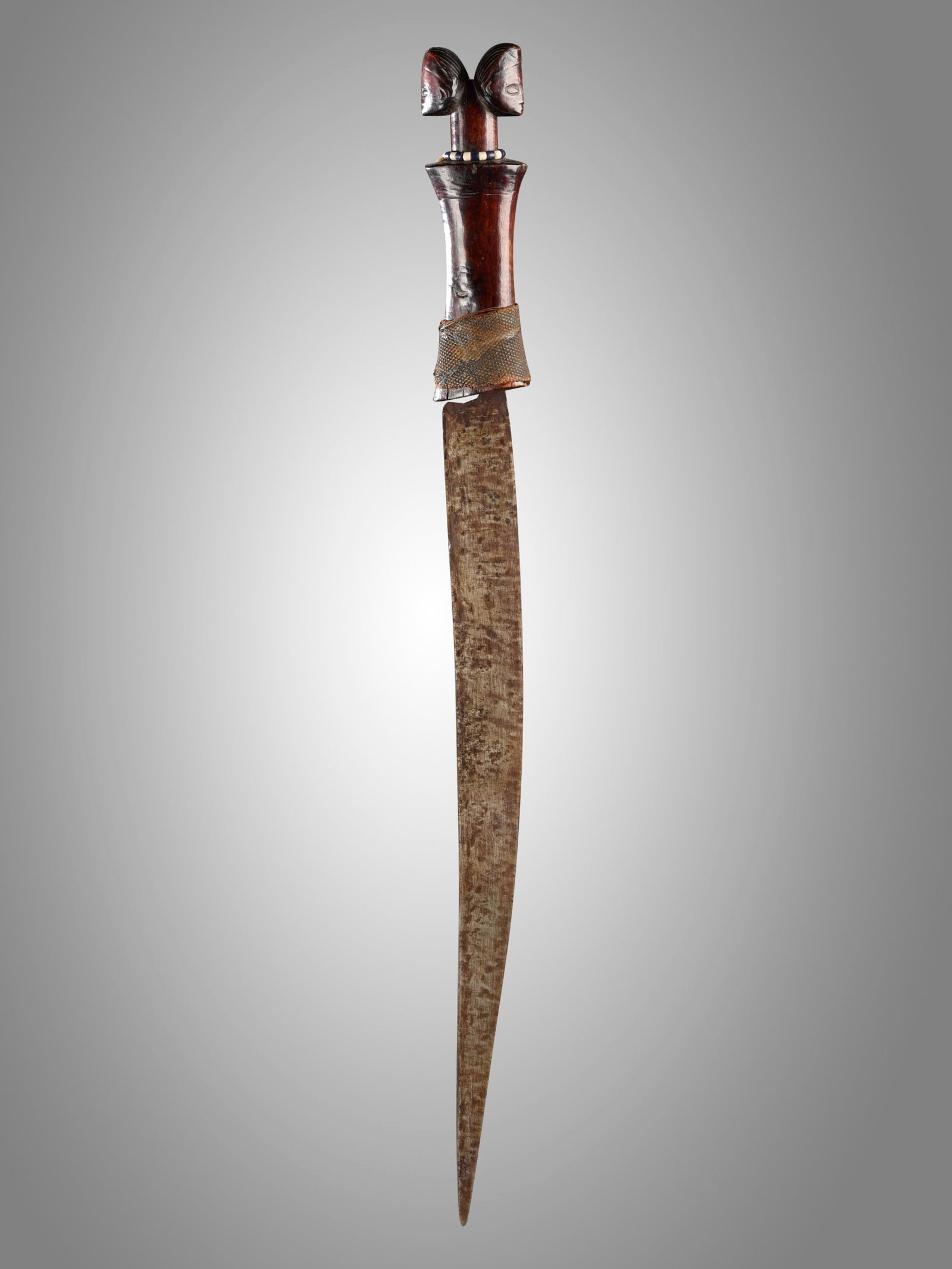 A Luba (?) Ceremonial Knife: Zeremonial-Messer Luba (?), Tabwa (?), DR Kongo Ohne Sockel / without base Holz, Eisen, Textil, Glasperlen. L 71,5 cm. Provenienz: Helmut (1931-2021) und Marianne Zimmer, Zürich. Zeremonialwaffen