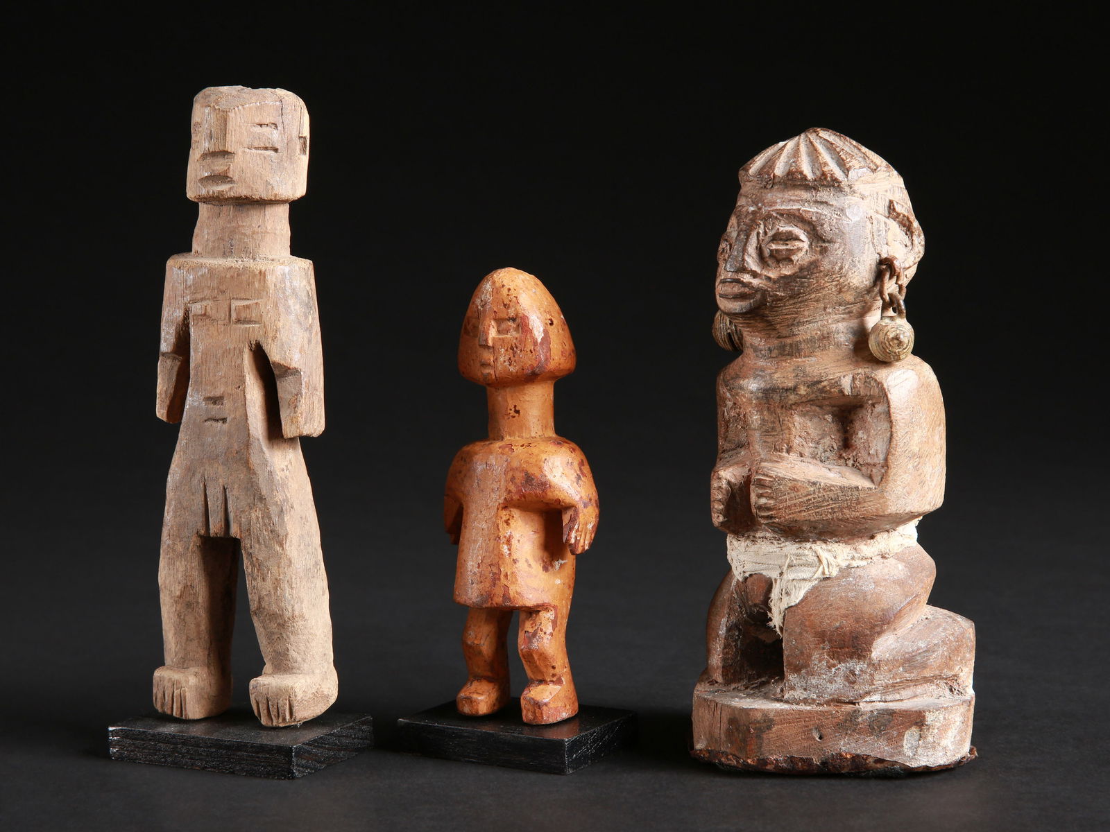 A Fon and two Adan Figures: 2 Figuren der Adan und eine weitere der Fon Adan / Fon, Ghana / Benin Holz, Eisen, Textil. H 13 - 18,5 cm. Provenienz: Christian Zingg (1956-2023), La Chaux-de-Fonds, Schweiz. Rechts: knieende Figur d