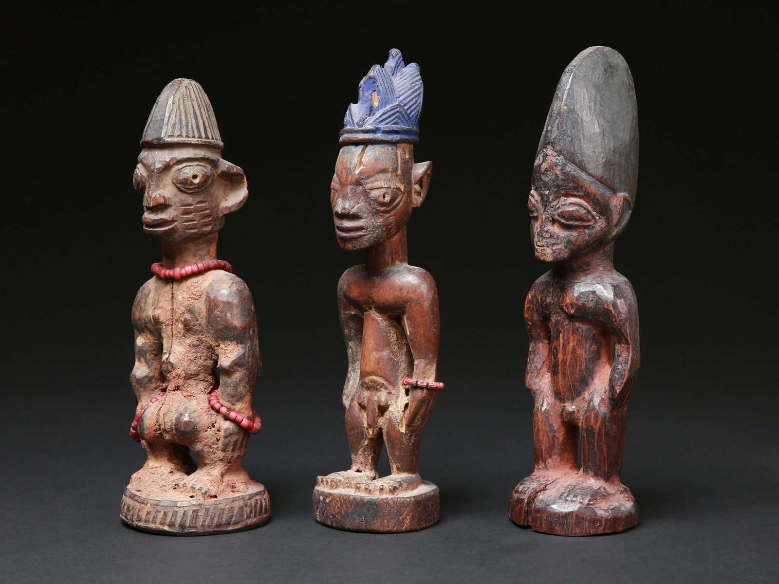 3 Yoruba Twin Figures, "ere ibeji": 3 Zwillingsfiguren, "ere ibeji" Yoruba, Nigeria Ohne Sockel / without base Holz, Glasperlen. H 24 - 26 cm. Provenienz: Hans-Joachim Struck (1934-2016), 1980er Jahre in Nigeria erworben. Über Zwil