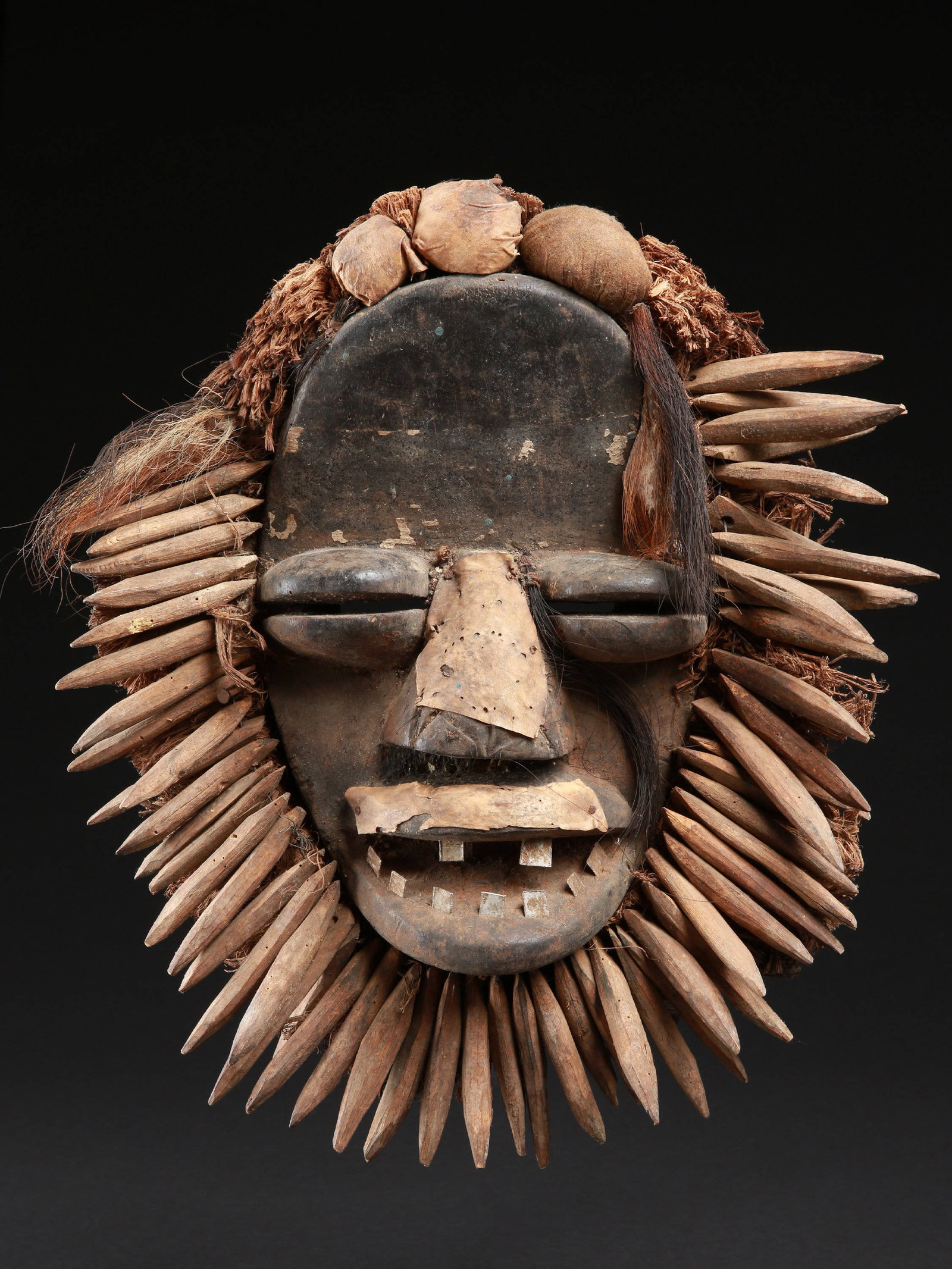A Wè-Guéré Mask: Gesichtsmaske Wè-Guéré, Côte d’Ivoire Ohne Sockel / without base Holz, Aluminium, Raphia, Leder, div. Fetischmaterial. H 37 cm. Provenienz: - Centre des Sciences Humaines, Abidjan. - 1969: Jean-