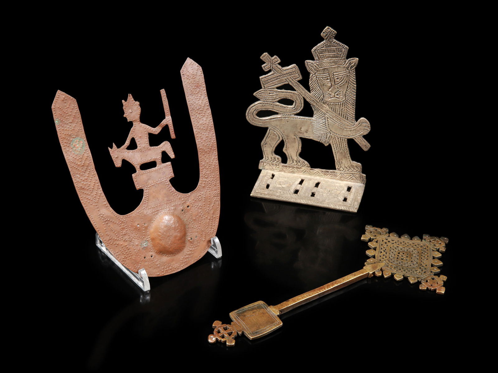 An Ethiopian Hand Cross "mäsqäl", a Bookend and a Copperwork: 1 Hand-Kreuz "mäsqäl", 1 Buchstütze, 1 Kupferarbeit Äthiopien Ohne Sockel / without base Kupferlegierung. H 16 - 25,5 cm. Provenienz: Gérald Minkoff (1937-2009) und Muriel Ole