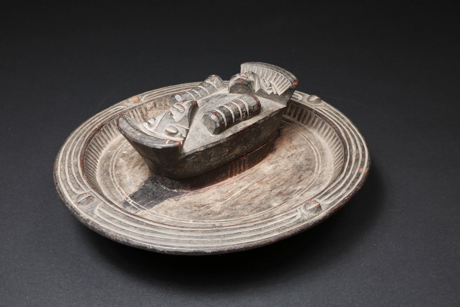 An Igbo Dish (Container with Lid) for Kola Nuts, "okwa oji": Kolanuss-Schale und -Behälter, "okwa oji" Igbo. Nigeria Ohne Sockel / without base Holz. H 16 cm. L 39 cm. Provenienz: Hans-Joachim Struck (1934-2016), 1980er Jahre in Nigeria erworben. Kolanussb